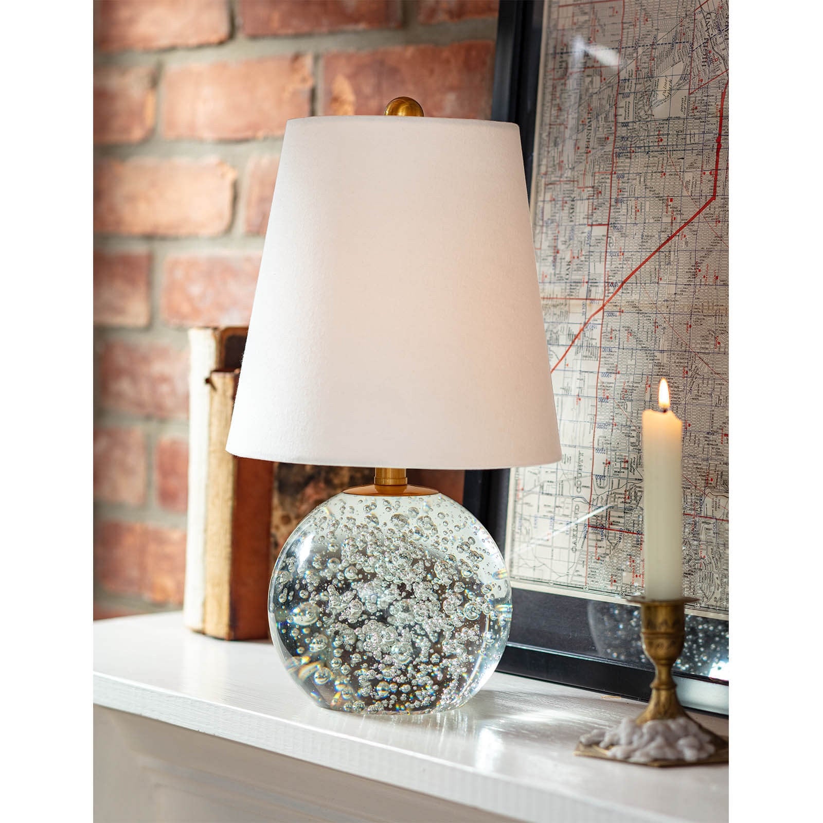 Bulle Crystal Mini Lamp (15" H) with a round clear crystal base containing internal bubbles, gilded neck, and a natural tapered linen shade.