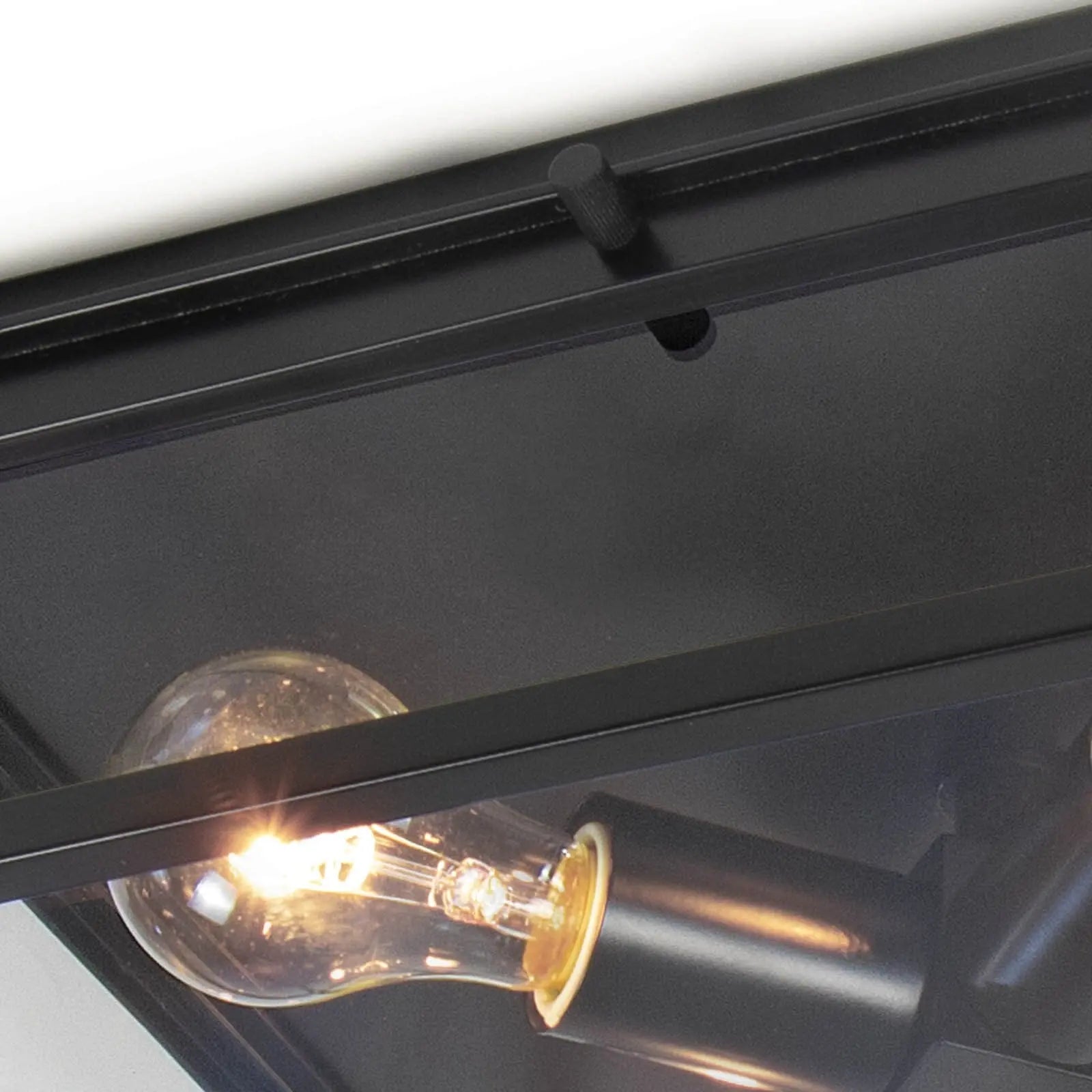 Close-up of a black industrial-style light fixture with a lit bulb.