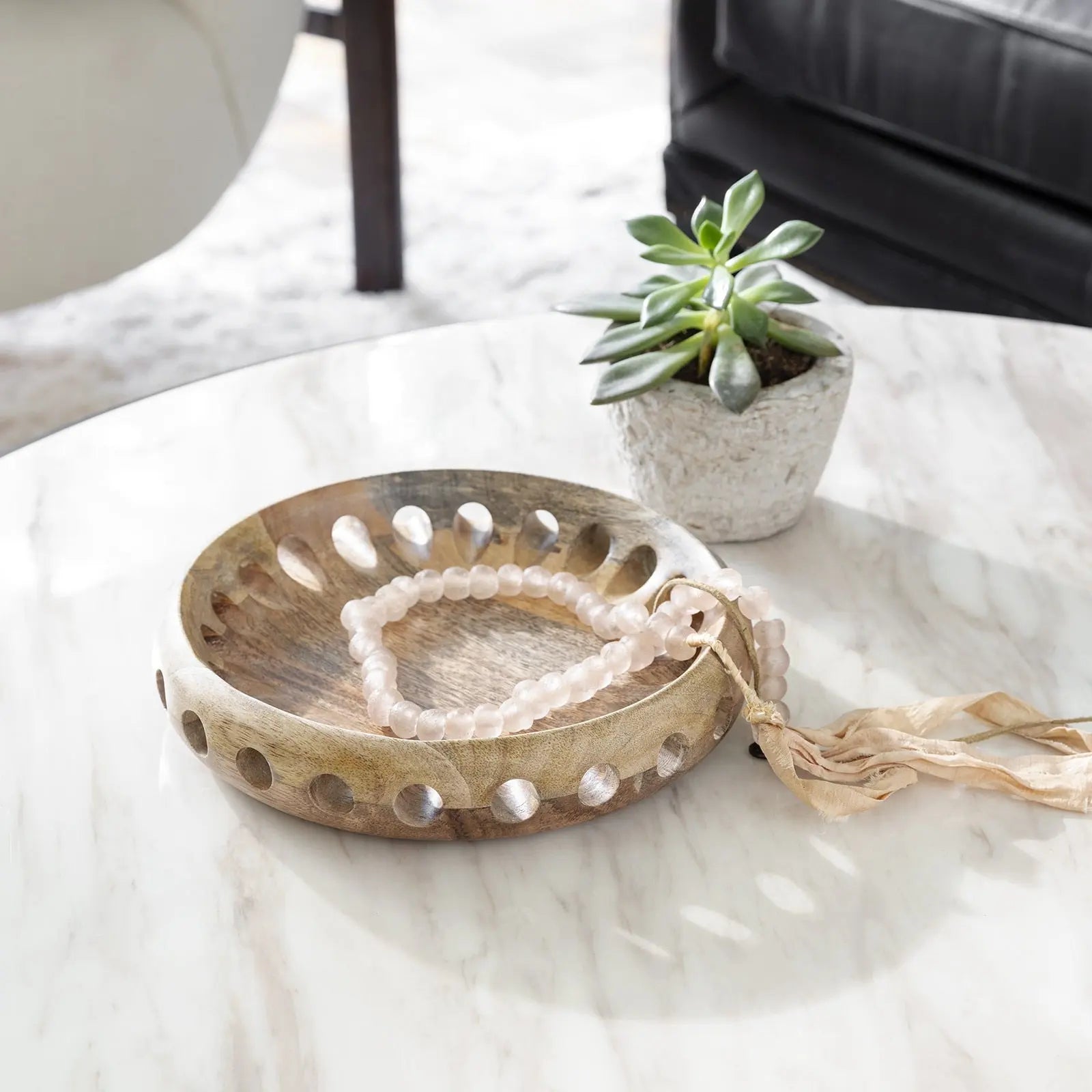 Wooden bowl with decorative items on a marble surface