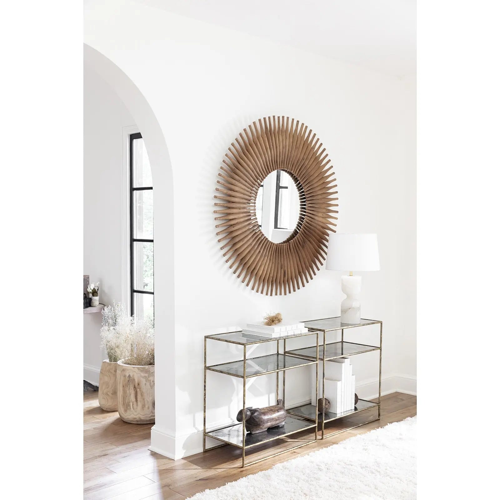 Modern interior with a sunburst mirror and glass console table.