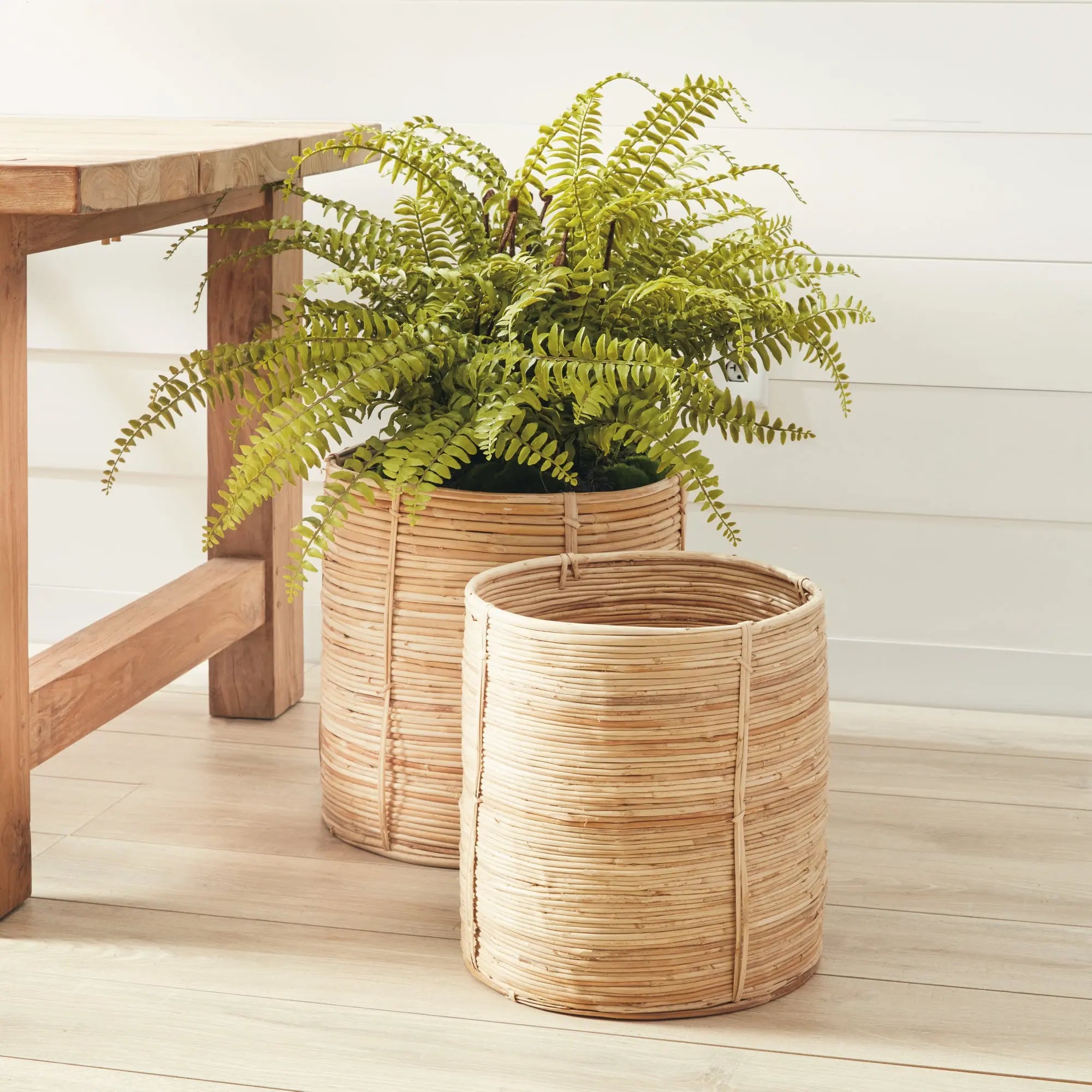 Two woven planters with a fern on a wooden deck