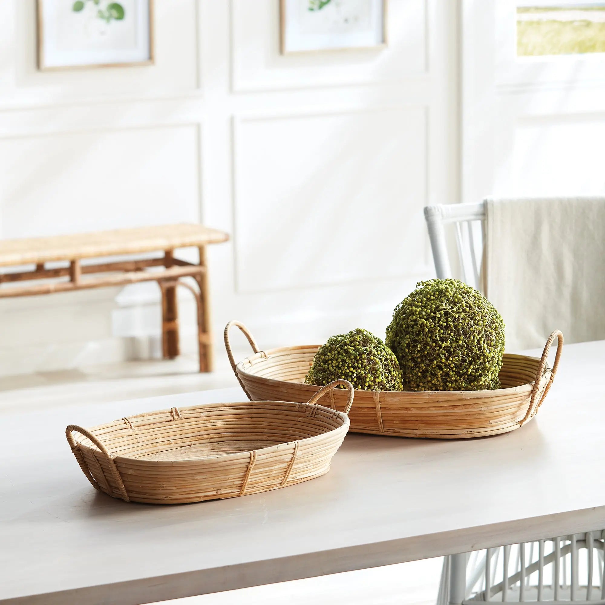 Two woven baskets with green decorative balls on a white surface in a bright room.