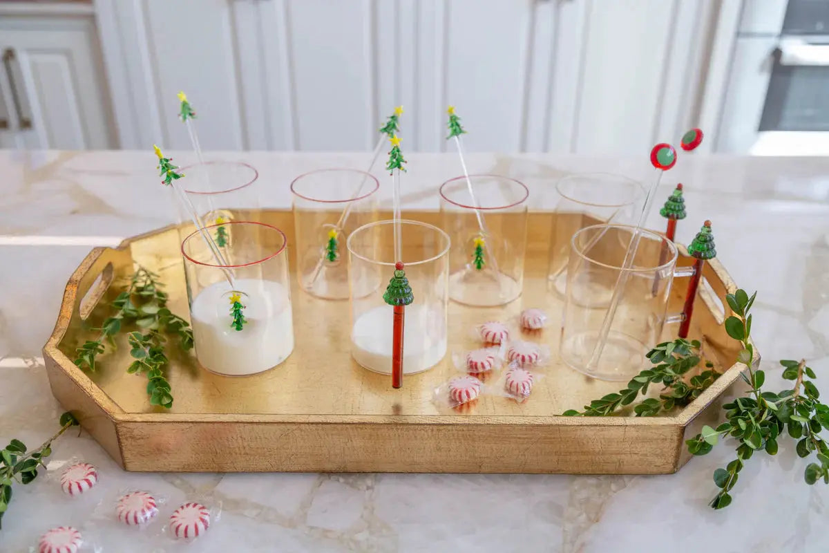 Decorative glasses with Christmas tree candles on a wooden tray.