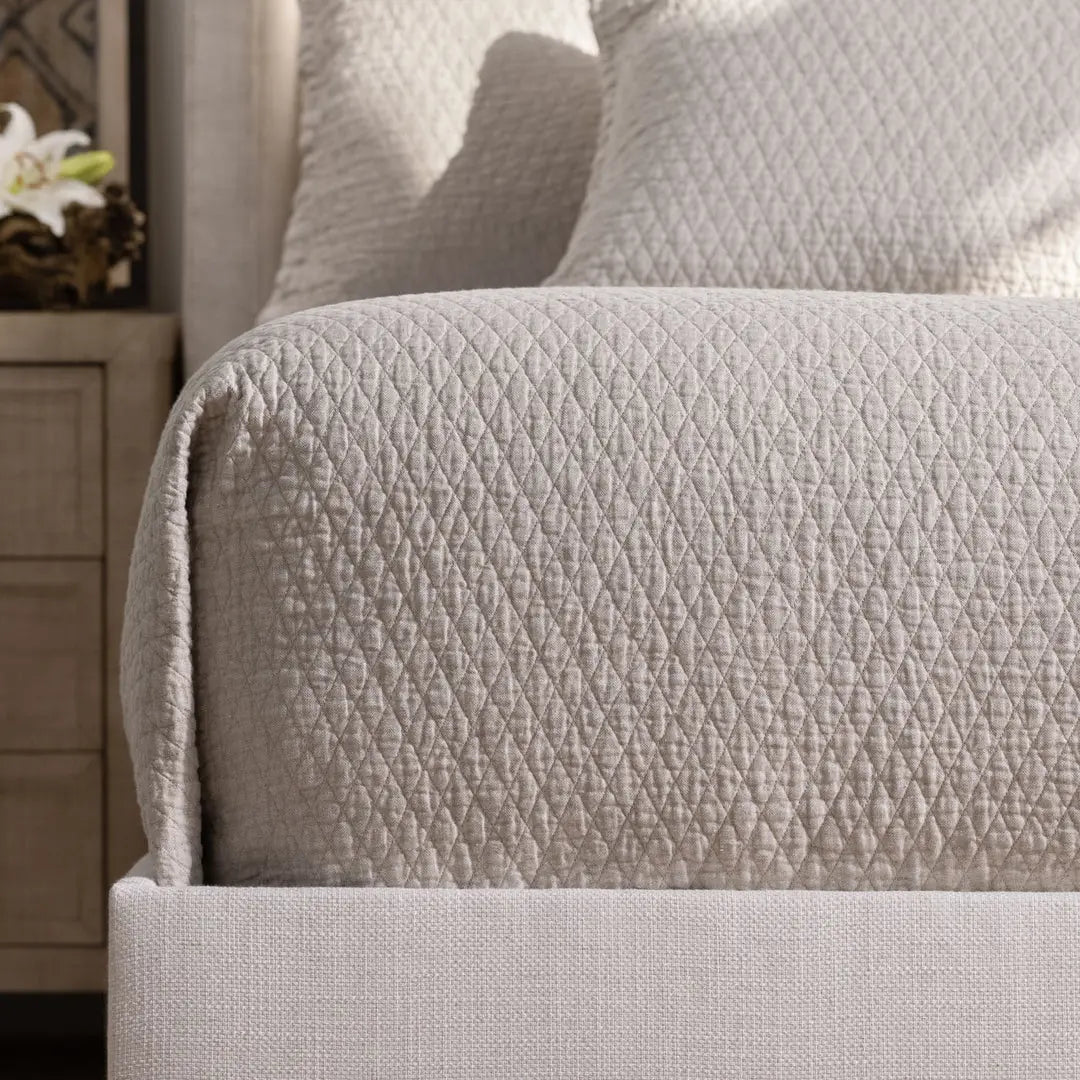 Dawn Diamond Quilted Queen Coverlet in the warm neutral color, showing the quilted texture and flange edge on a bed.
