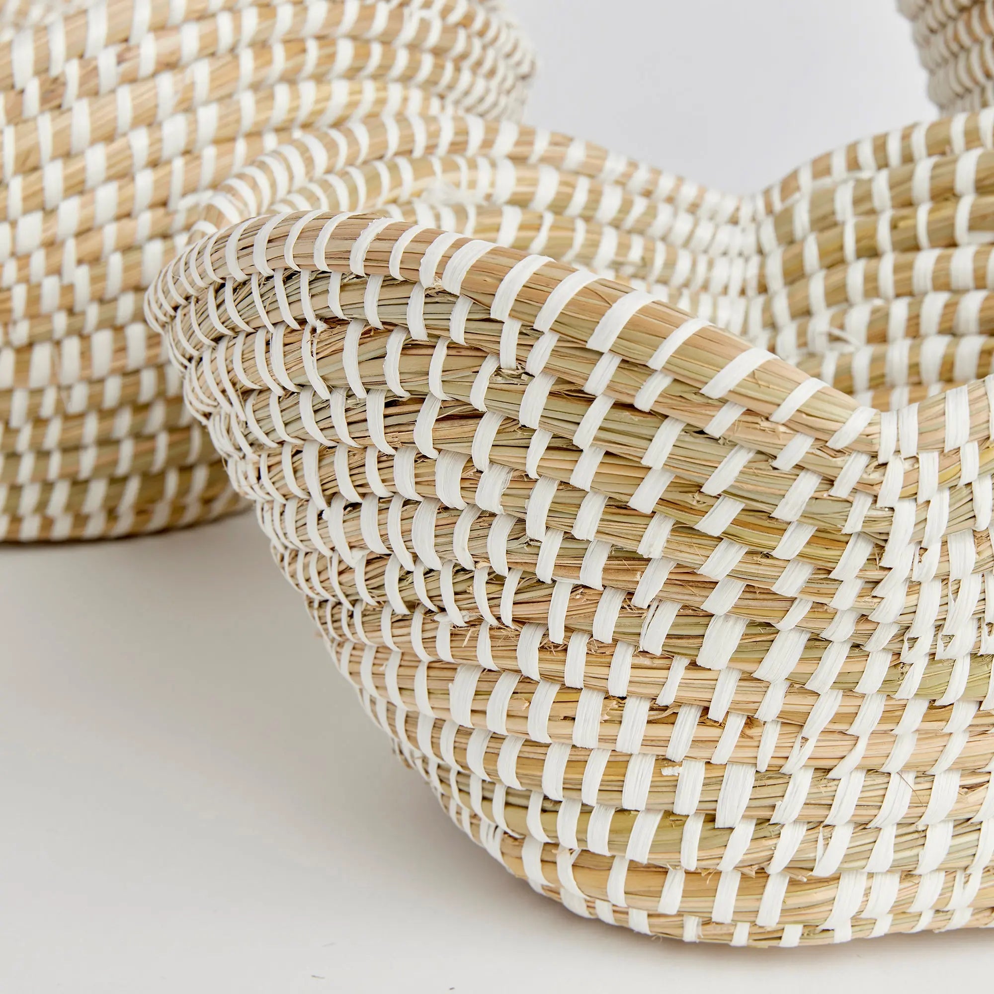 Stack of woven baskets with white and beige stripes on a light background