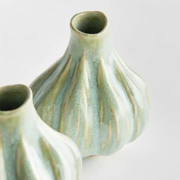A set of two small round bud vases with a sculptural organic shape, finished in a thick multi-tonal green reactive glaze with handcrafted artisan details.