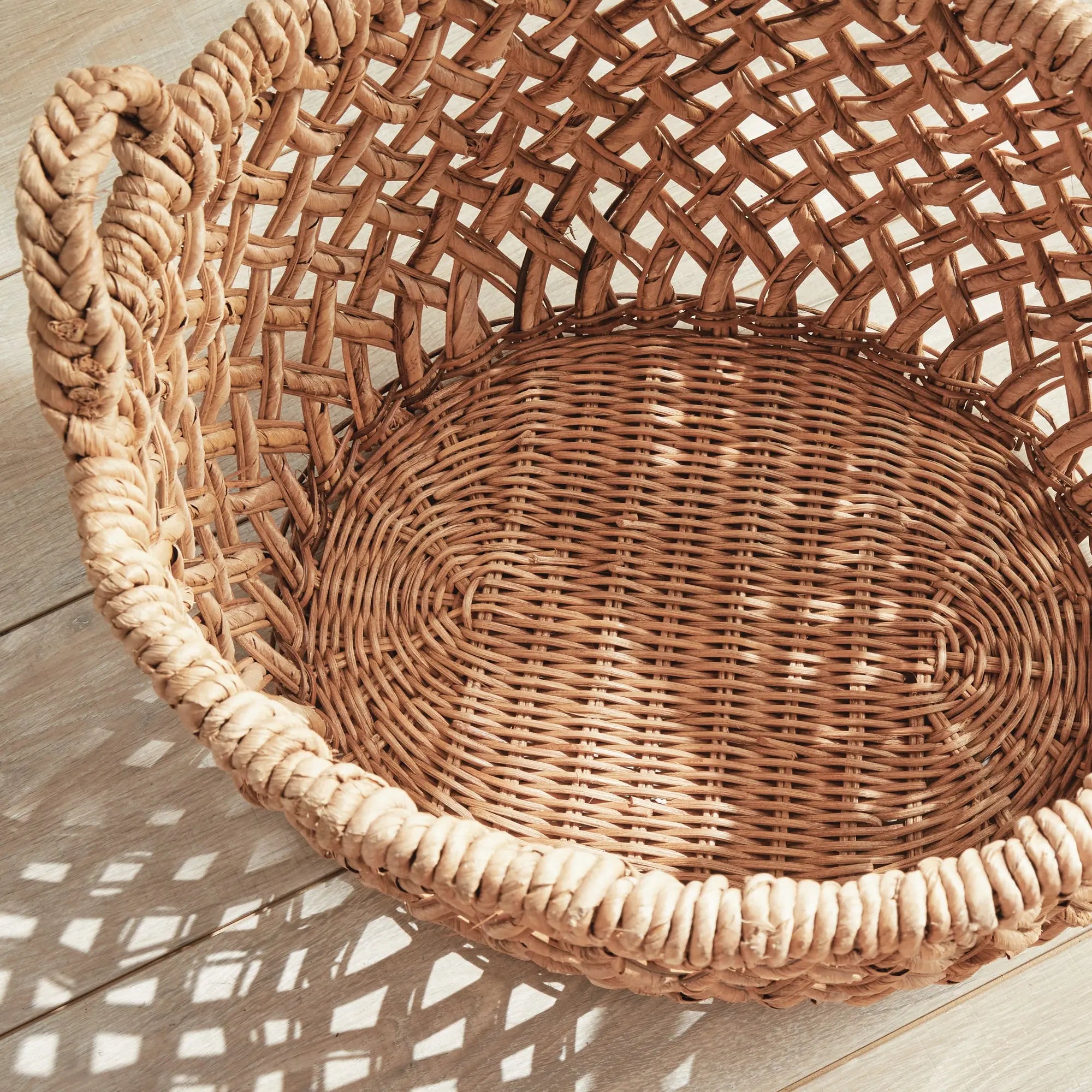 Emlyn Woven Storage Baskets with Handles – Set of 2 (Banana Leaf) - Woven basket on a wooden surface with natural light casting shadows
