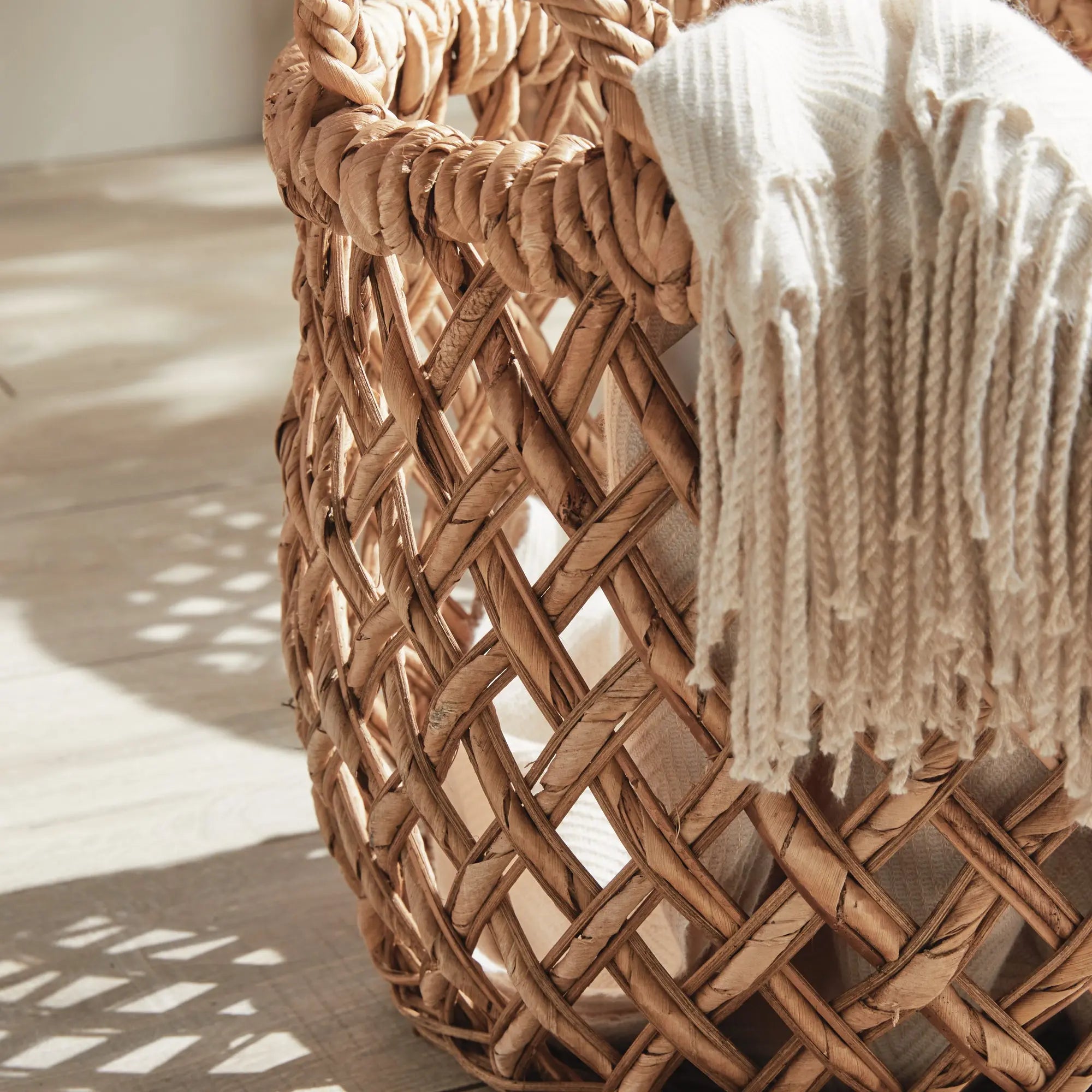 Emlyn Woven Storage Baskets with Handles – Set of 2 (Banana Leaf) - Woven basket with a white towel draped over it on a wooden floor.