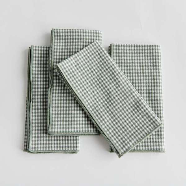 Set of four Viola Dinner Napkins made from soft, verdant green cotton, folded and tied with a grosgrain ribbon.
