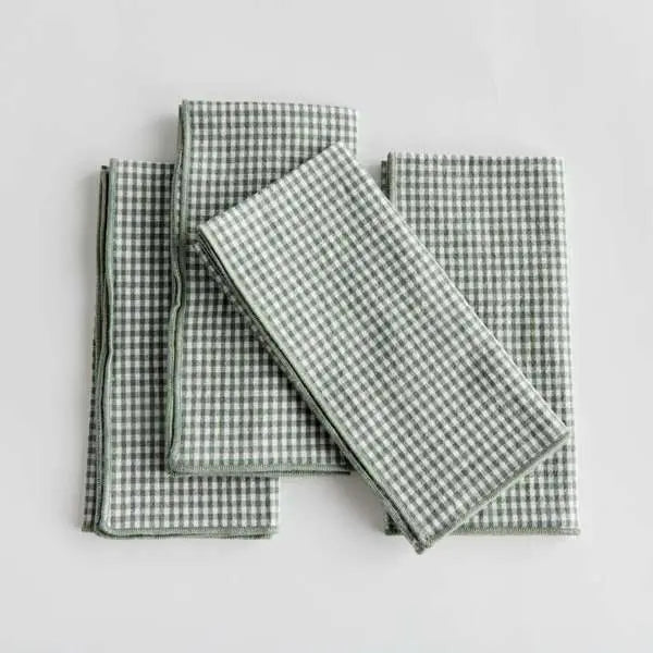 Set of four Viola Dinner Napkins made from soft, verdant green cotton, folded and tied with a grosgrain ribbon.