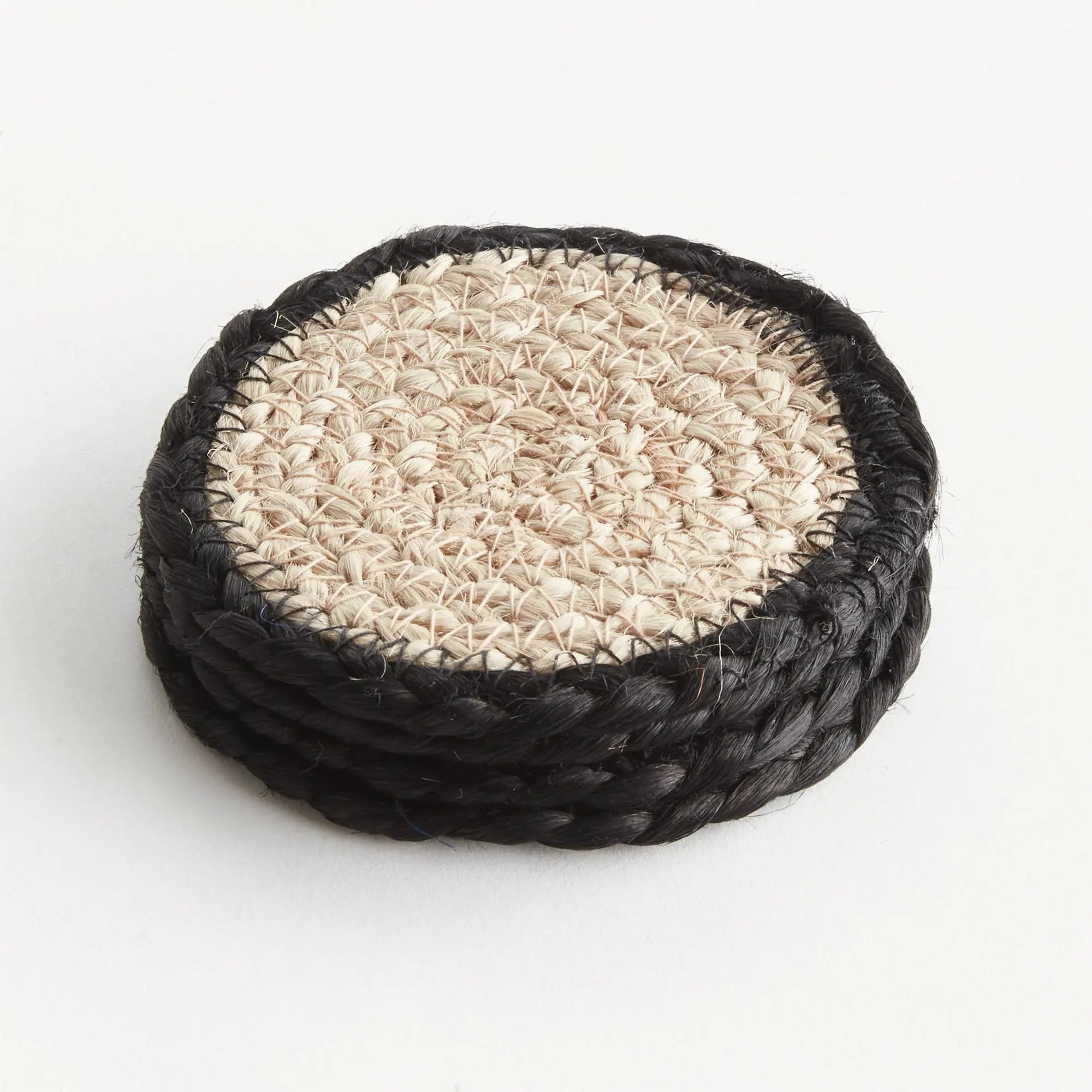 Round woven coaster with black rim on a white background