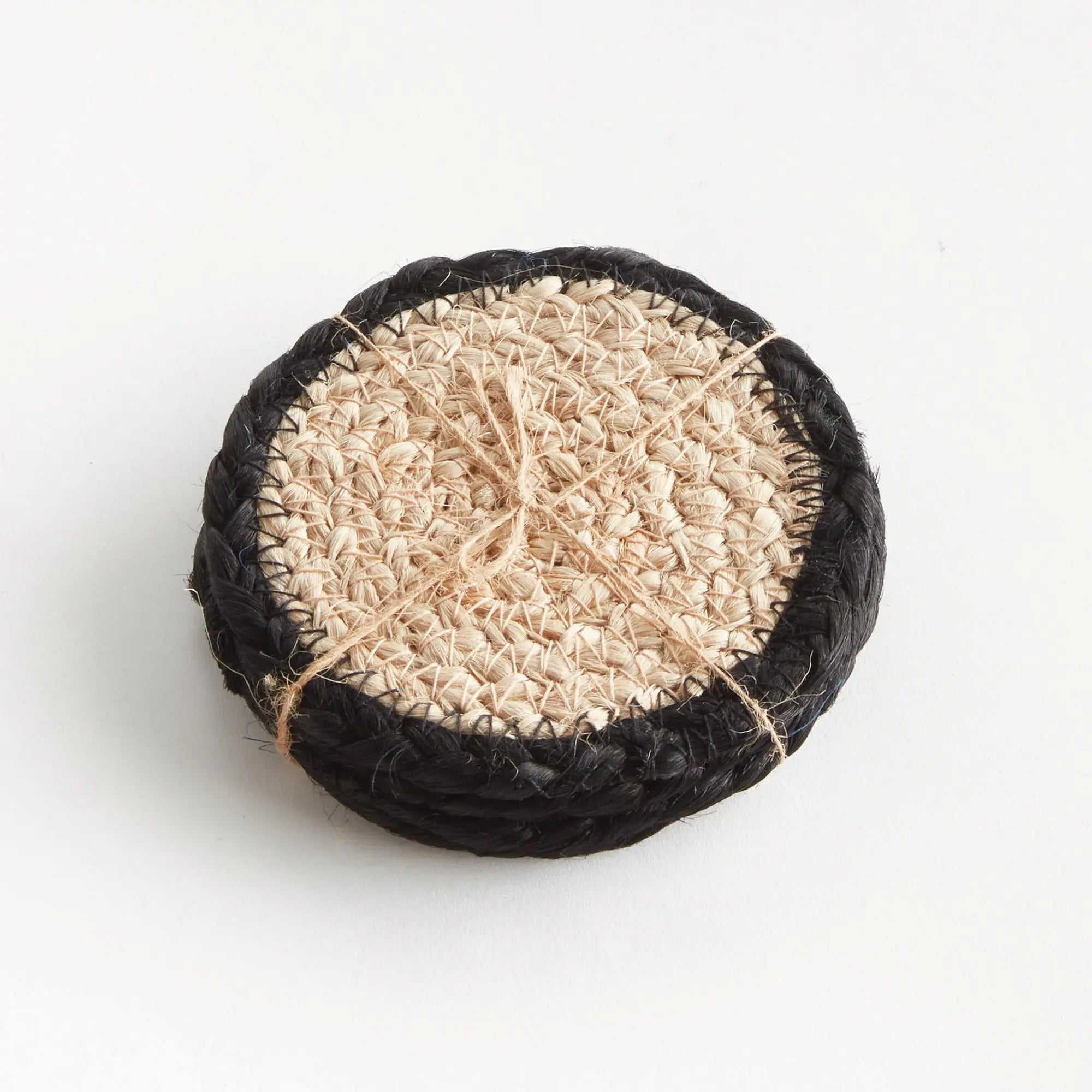 Round woven coaster with black rim on a white background