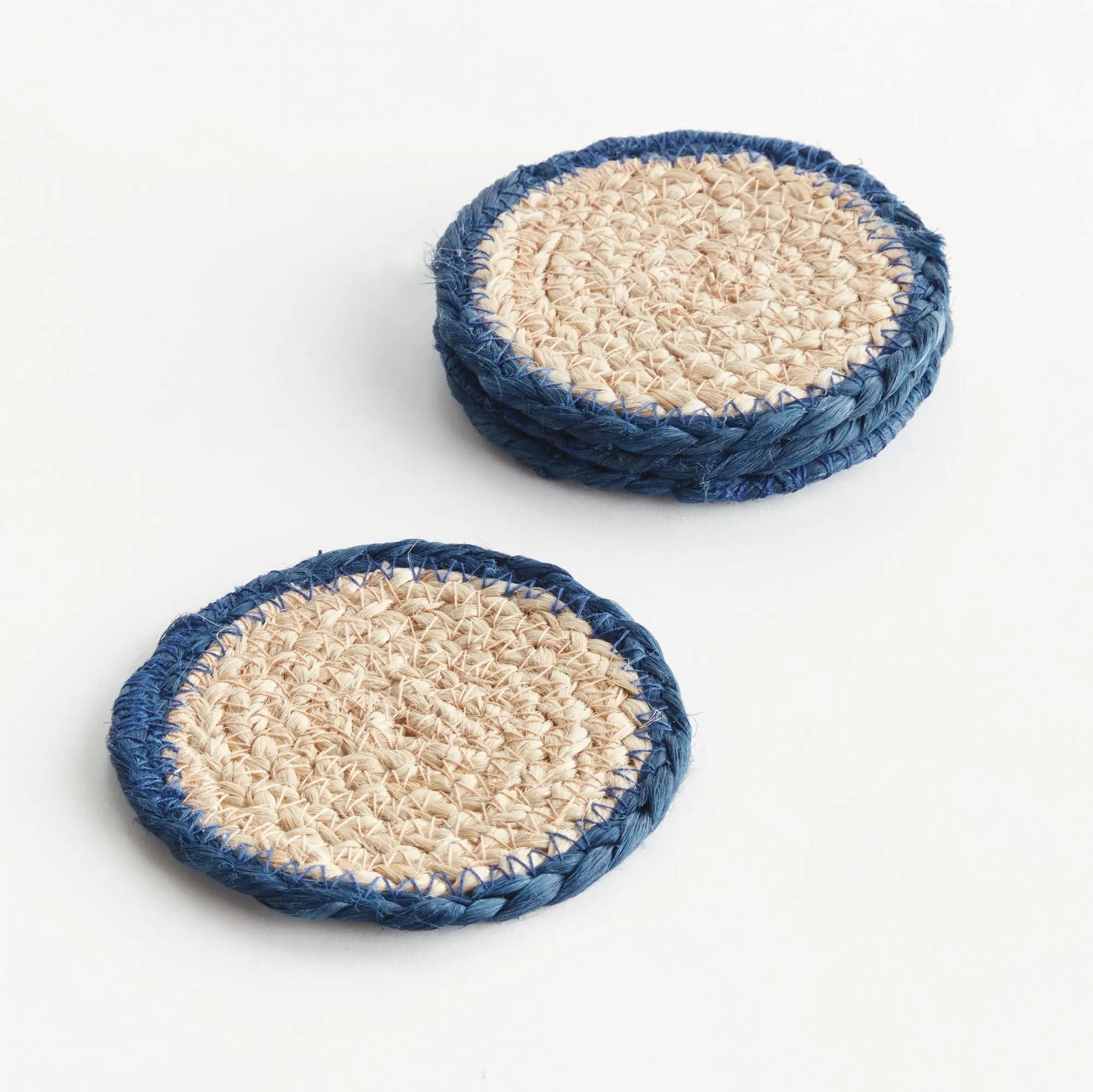 Two round woven coasters with blue rims on a white background