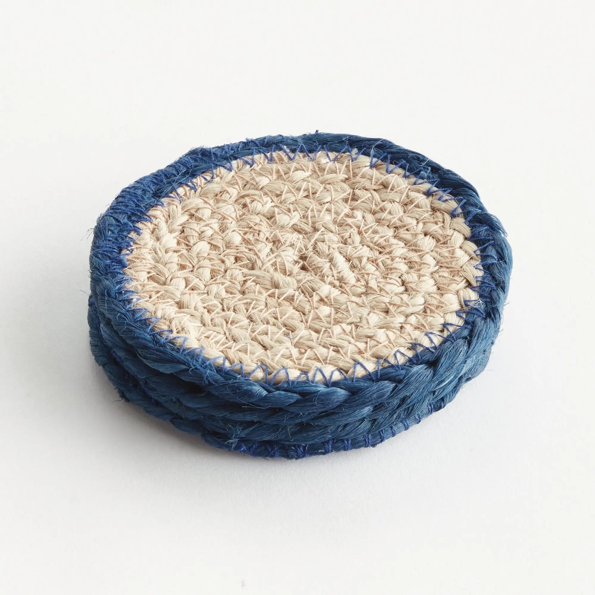Stack of blue and beige woven coasters on a white background