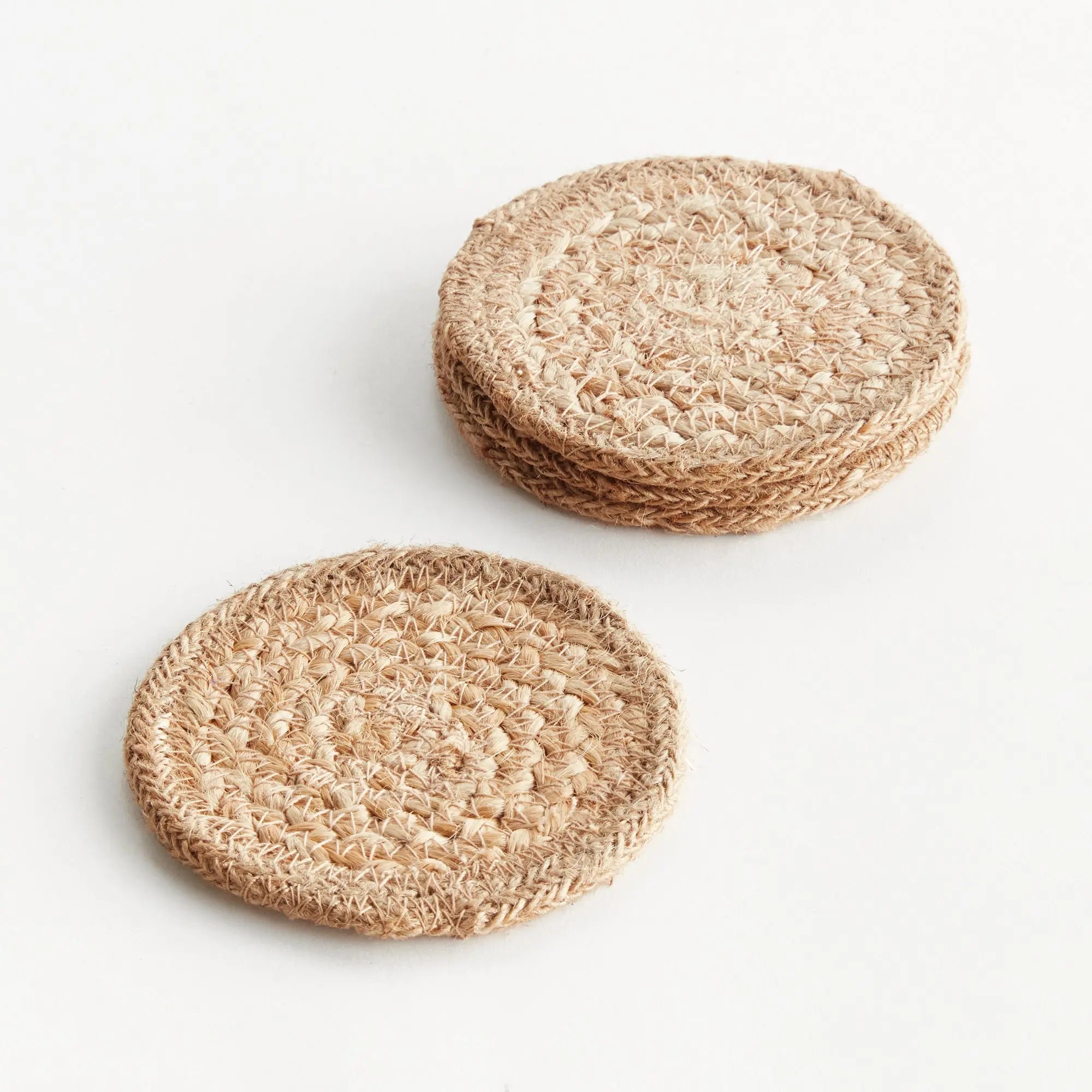 Two round, beige woven coasters on a white background