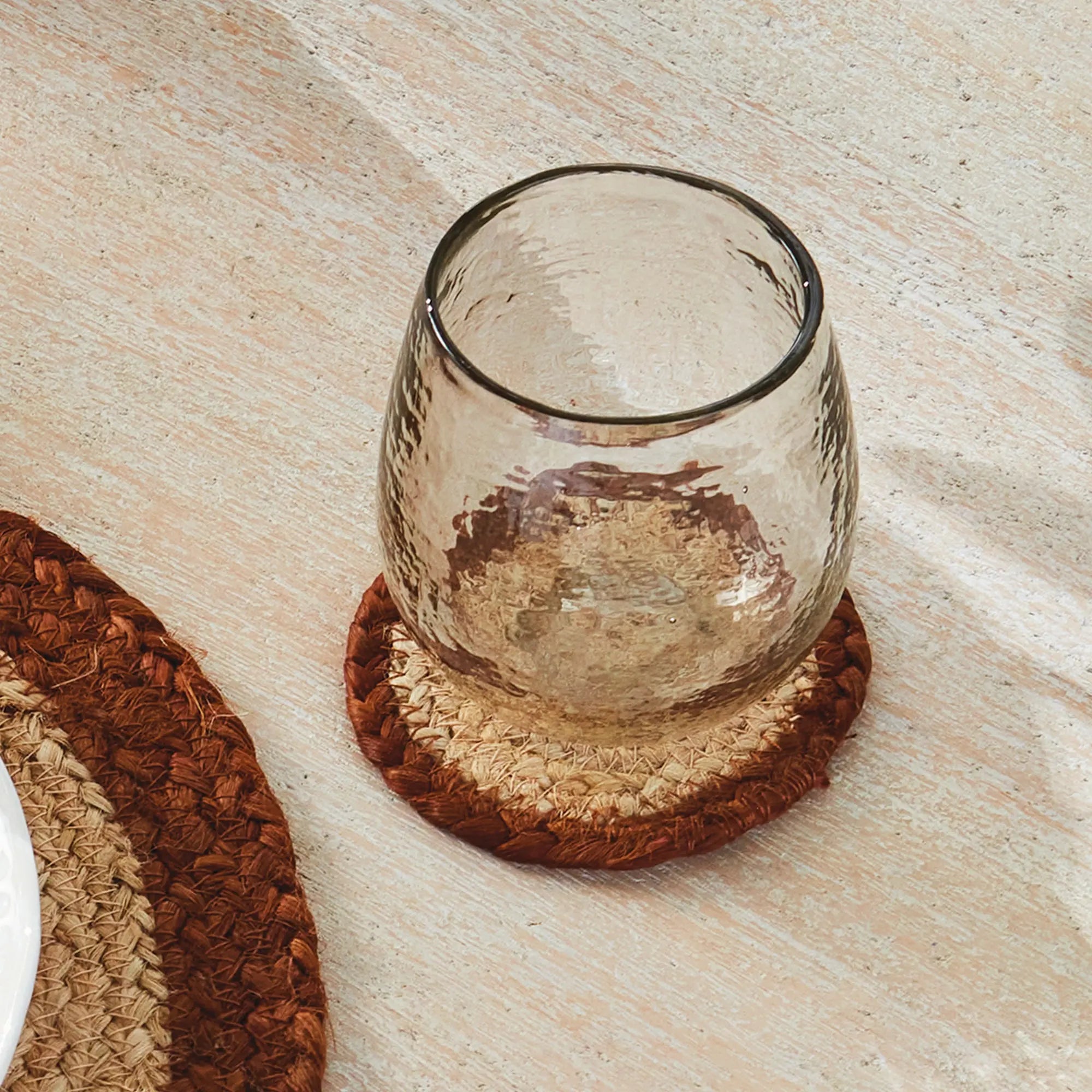Clear glass on a woven coaster on a wooden surface