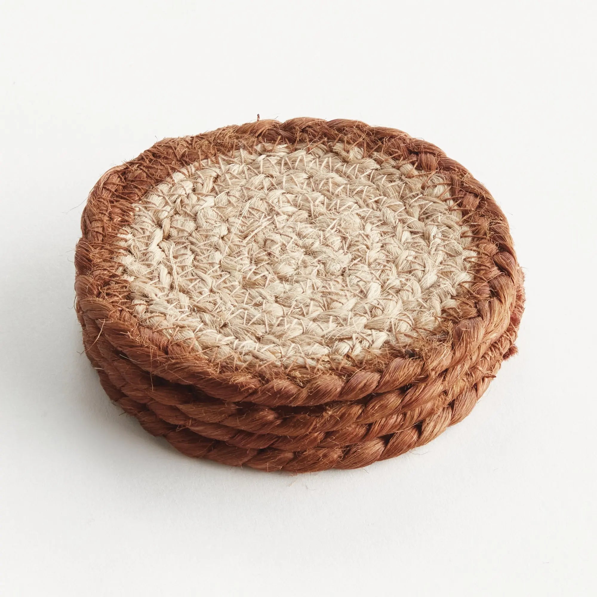 Stack of woven coasters with brown rim and beige center on a white background