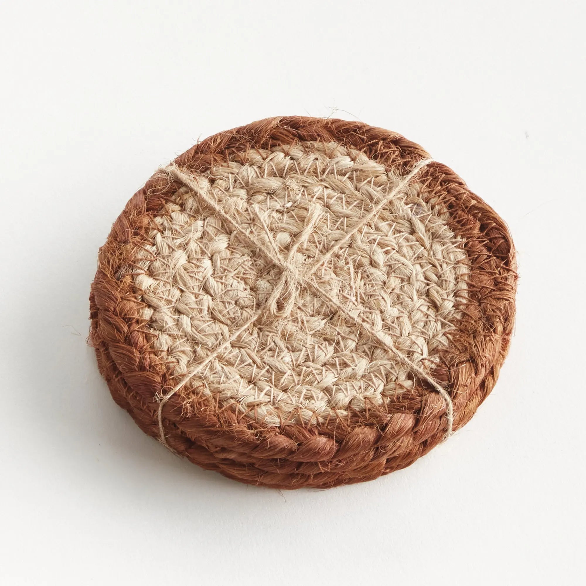 Round woven coaster with a braided design on a white background