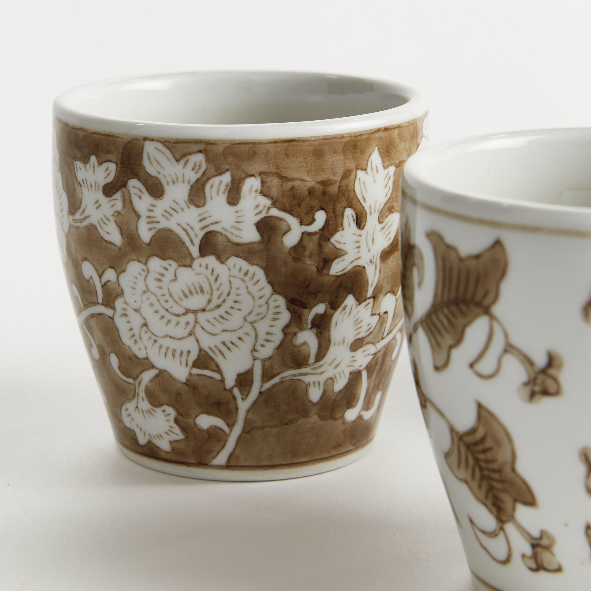 Two ceramic cups with floral patterns on a white background