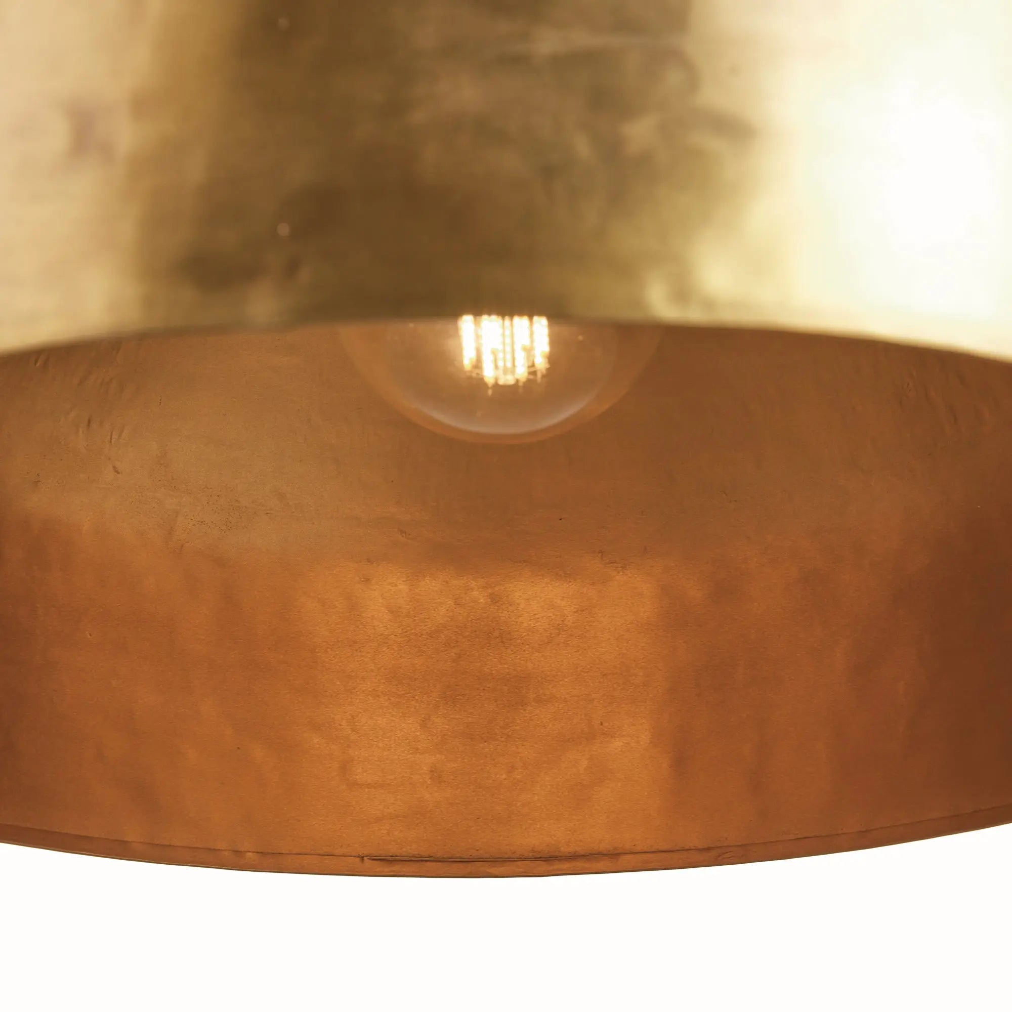 Close-up of a brass pendant light with a visible bulb inside.