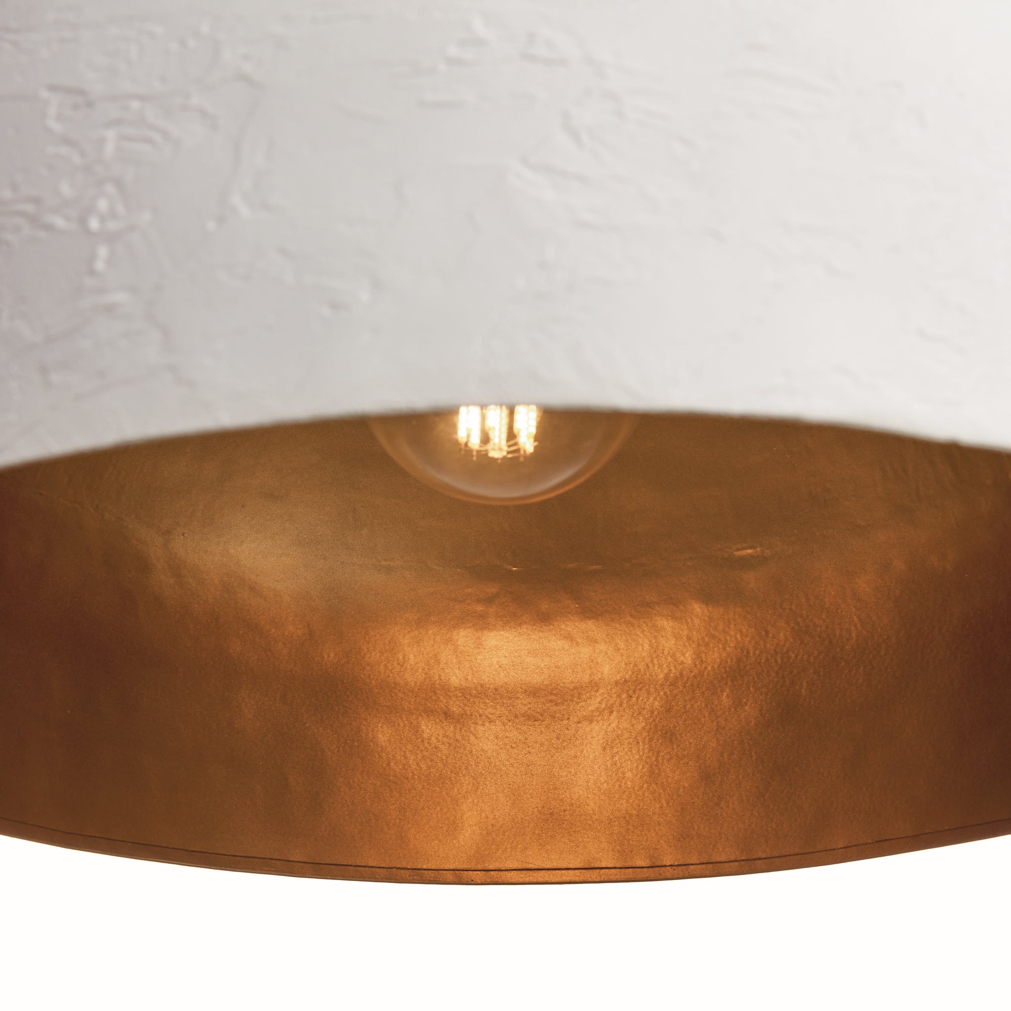 Close-up of a gold pendant light with a white wall background