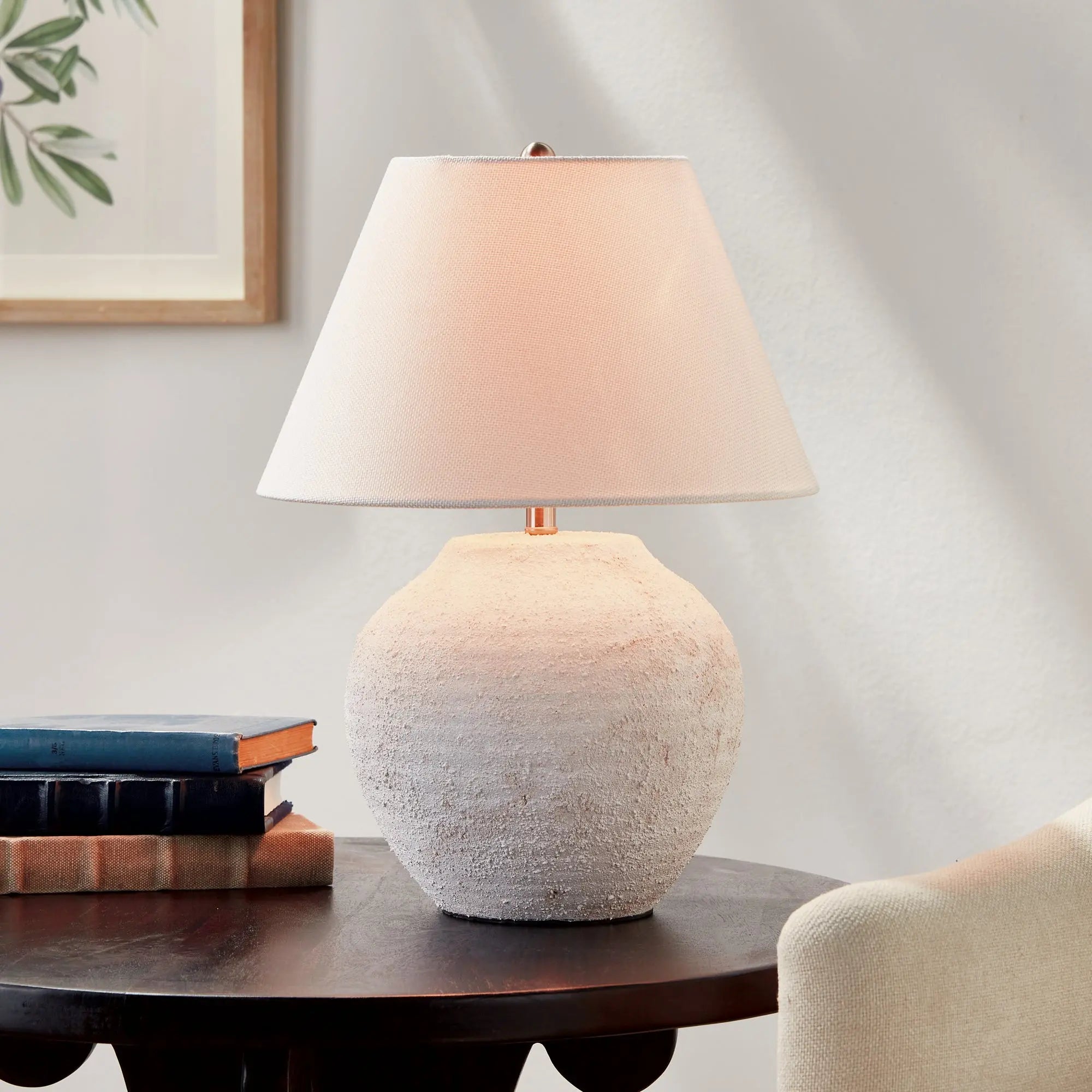 Theo Table lamp with textured base and white shade on a wooden table against a neutral wall.