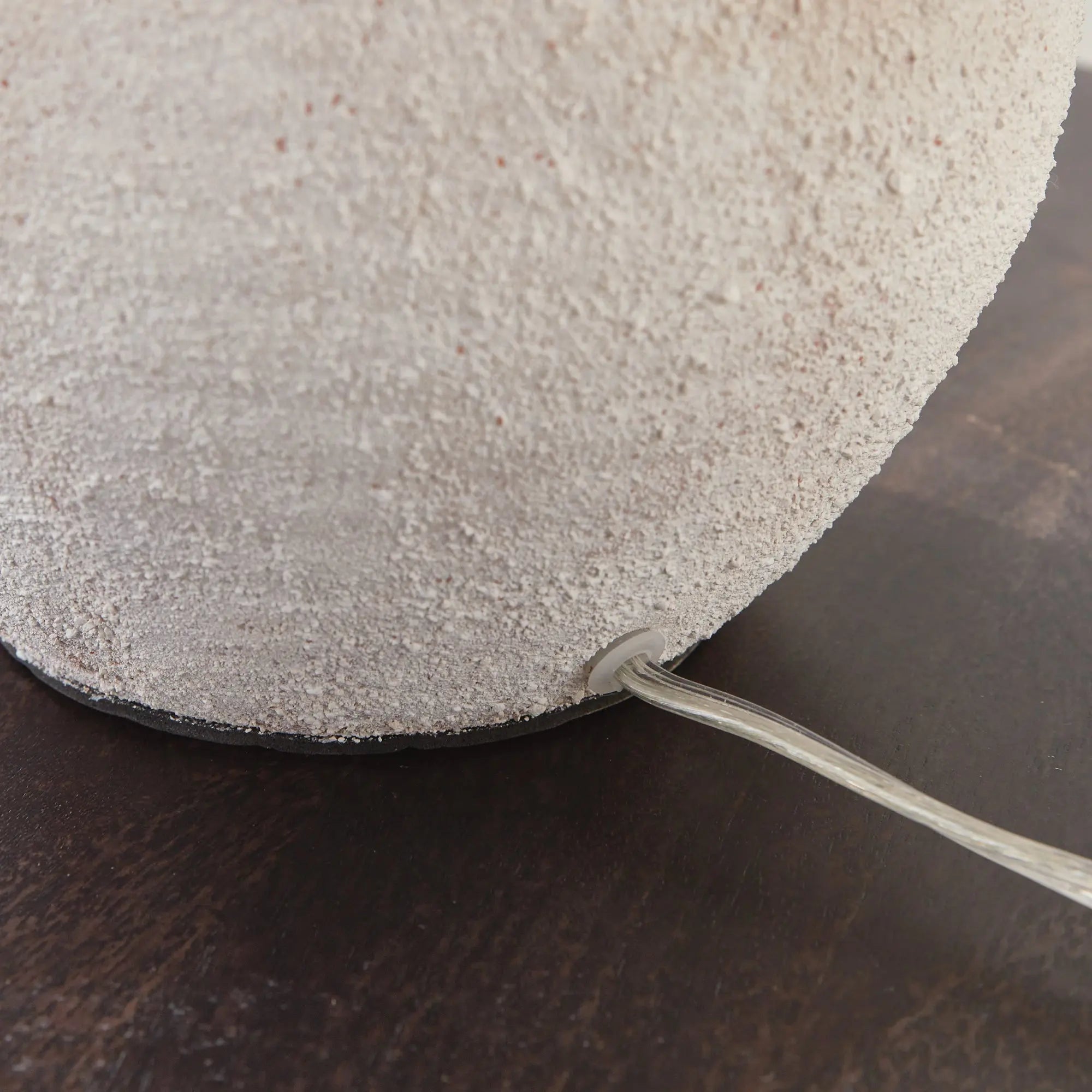 Theo Lamp - Round textured object with a wire on a dark surface