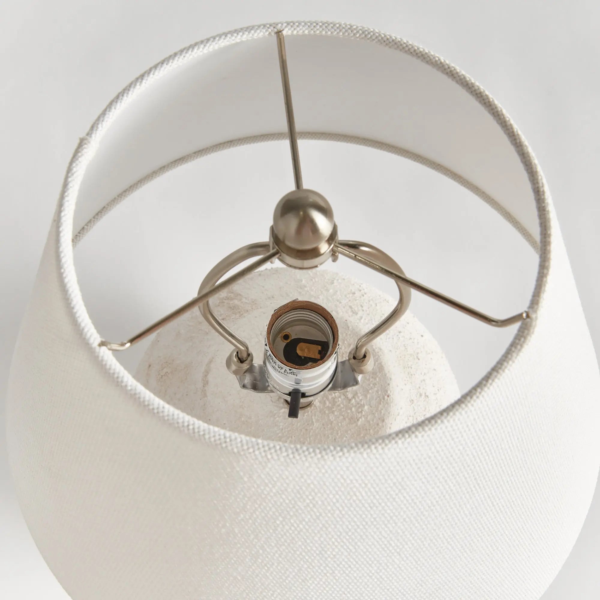 Theo Lamp - Close-up of a lampshade with a light bulb inside on a white background
