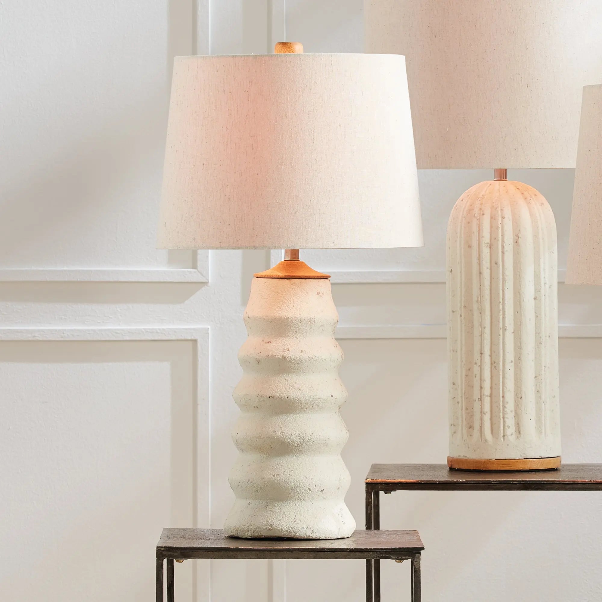 Adria Table Lamp with a textured, pitted, warm white ecomix base and a cream-colored tapered lamp shade. The lamp is shown from the front against a neutral background.