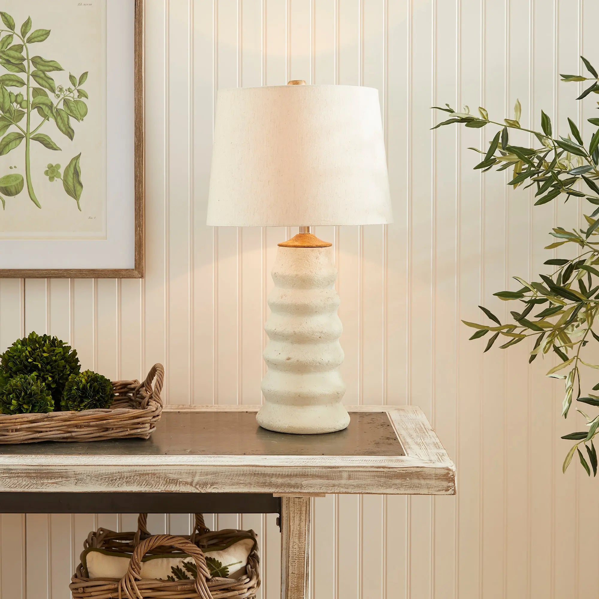 Adria Table Lamp with a textured, pitted, warm white ecomix base and a cream-colored tapered lamp shade. The lamp is shown from the front against a neutral background.