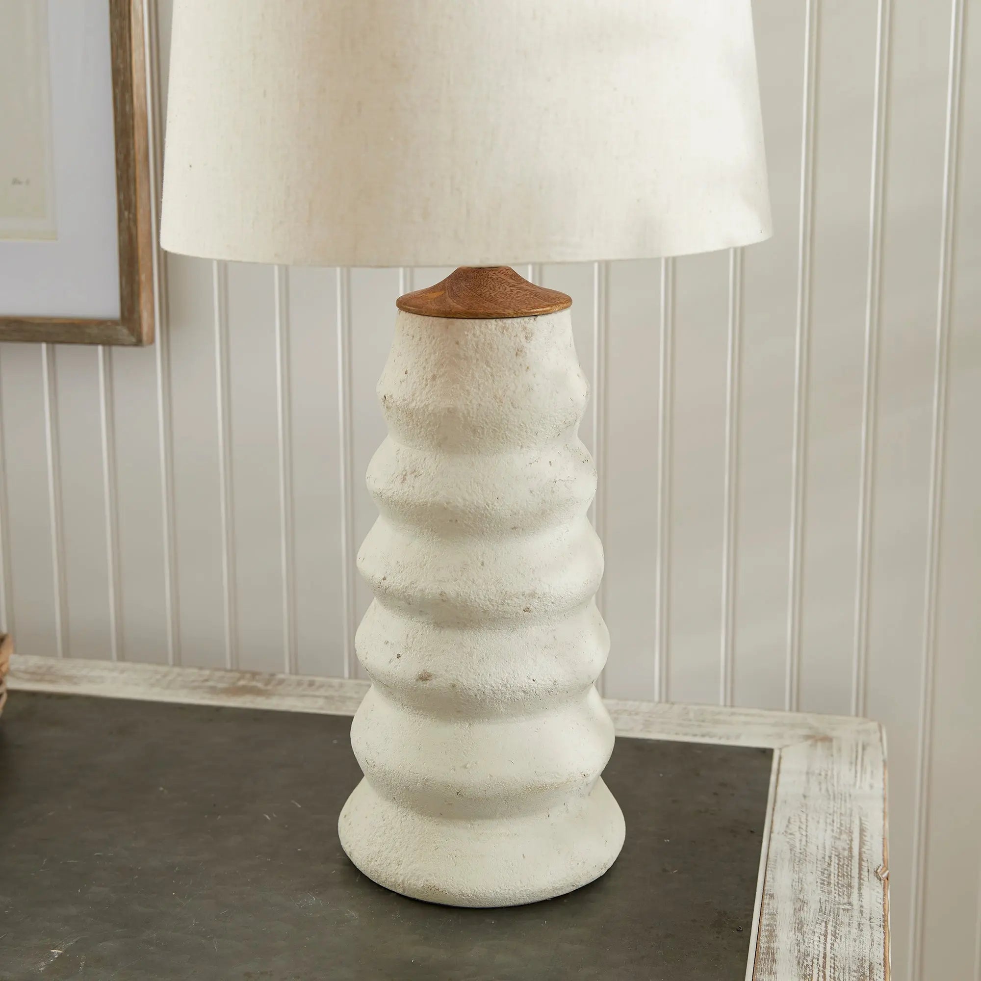 Adria Table Lamp with a textured, pitted, warm white ecomix base and a cream-colored tapered lamp shade. The lamp is shown from the front against a neutral background.