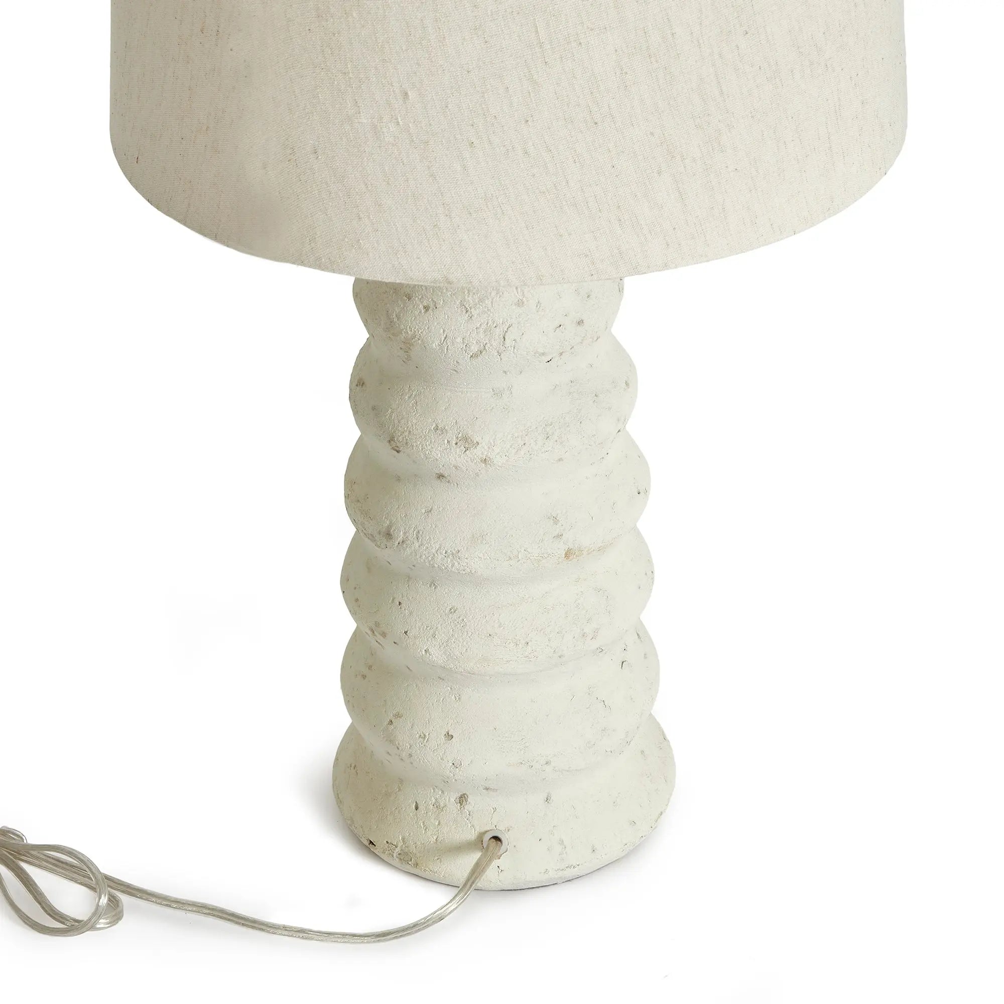 Adria Table Lamp with a textured, pitted, warm white ecomix base and a cream-colored tapered lamp shade. The lamp is shown from the front against a neutral background.