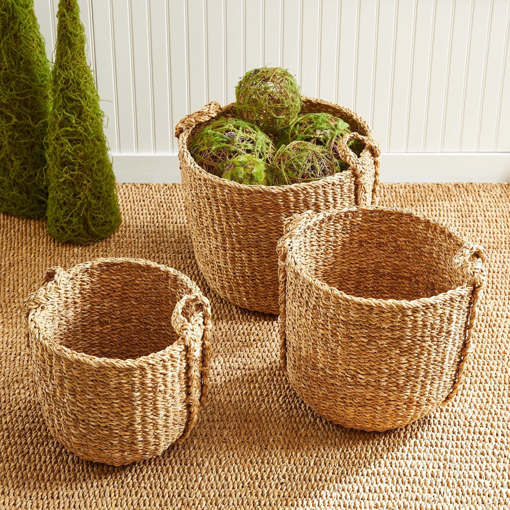 Three woven baskets on a textured surface with green decorative elements.