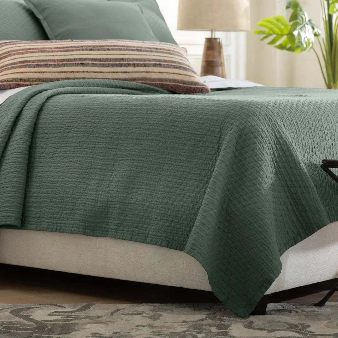 Dawn Diamond Quilted Queen Coverlet in the thunder green color showing the quilted texture and flange edge on a bed.