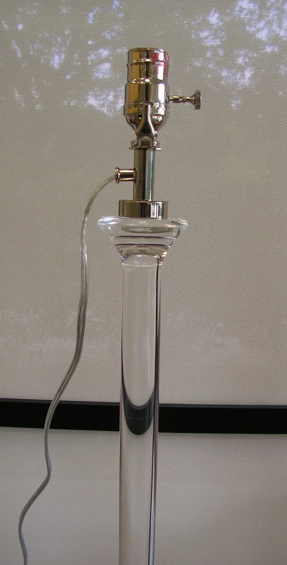 Ponte solid lead crystal table lamp with diamond-cut faceted base and cream-colored fabric drum shade, set on a console table.