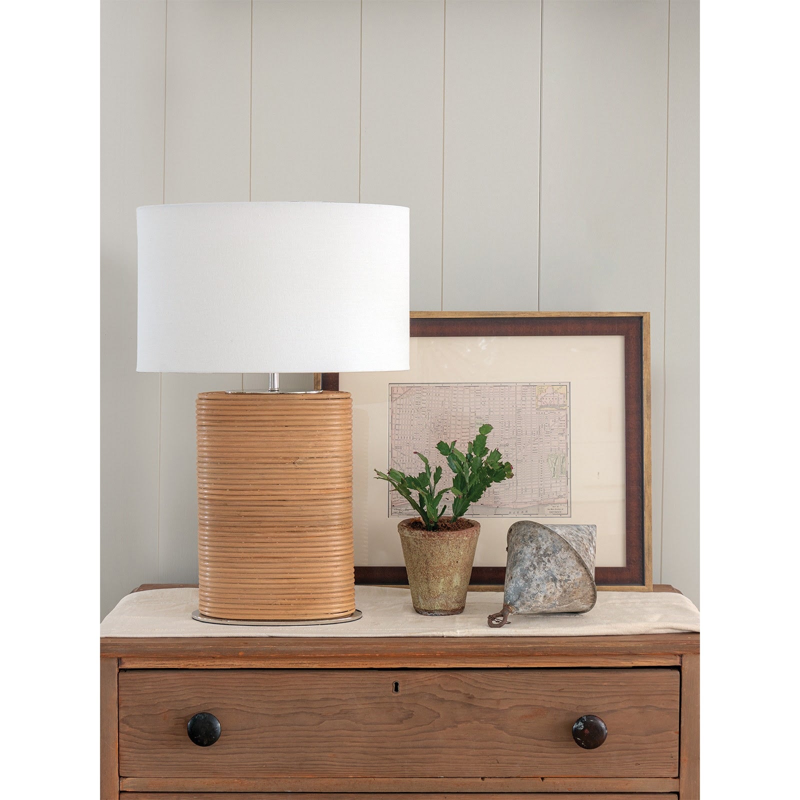 Wooden table with a lamp, plant, and decorative item against a light-colored wall.
