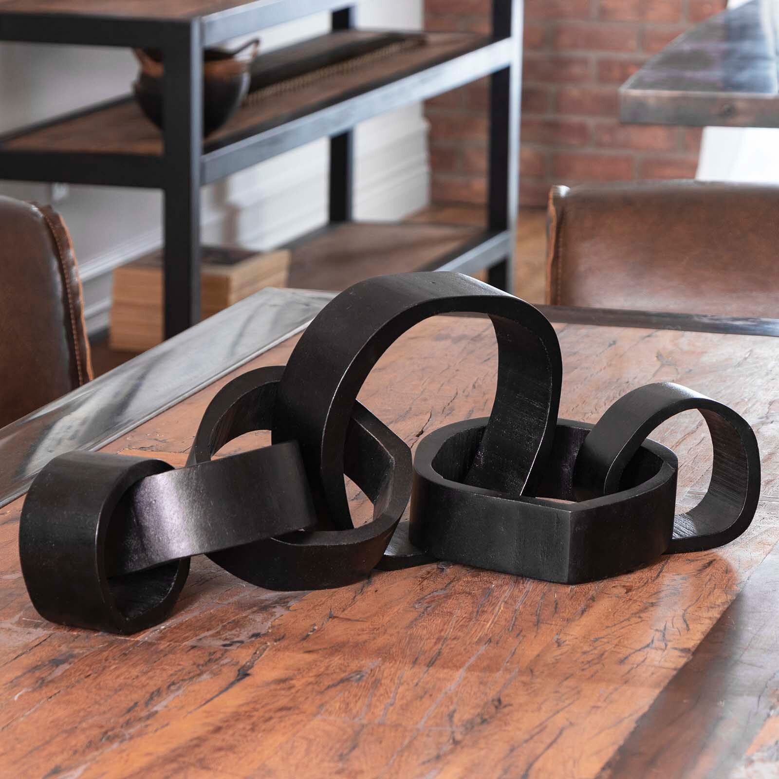 Decorative black metal sculpture on a wooden table with a blurred background