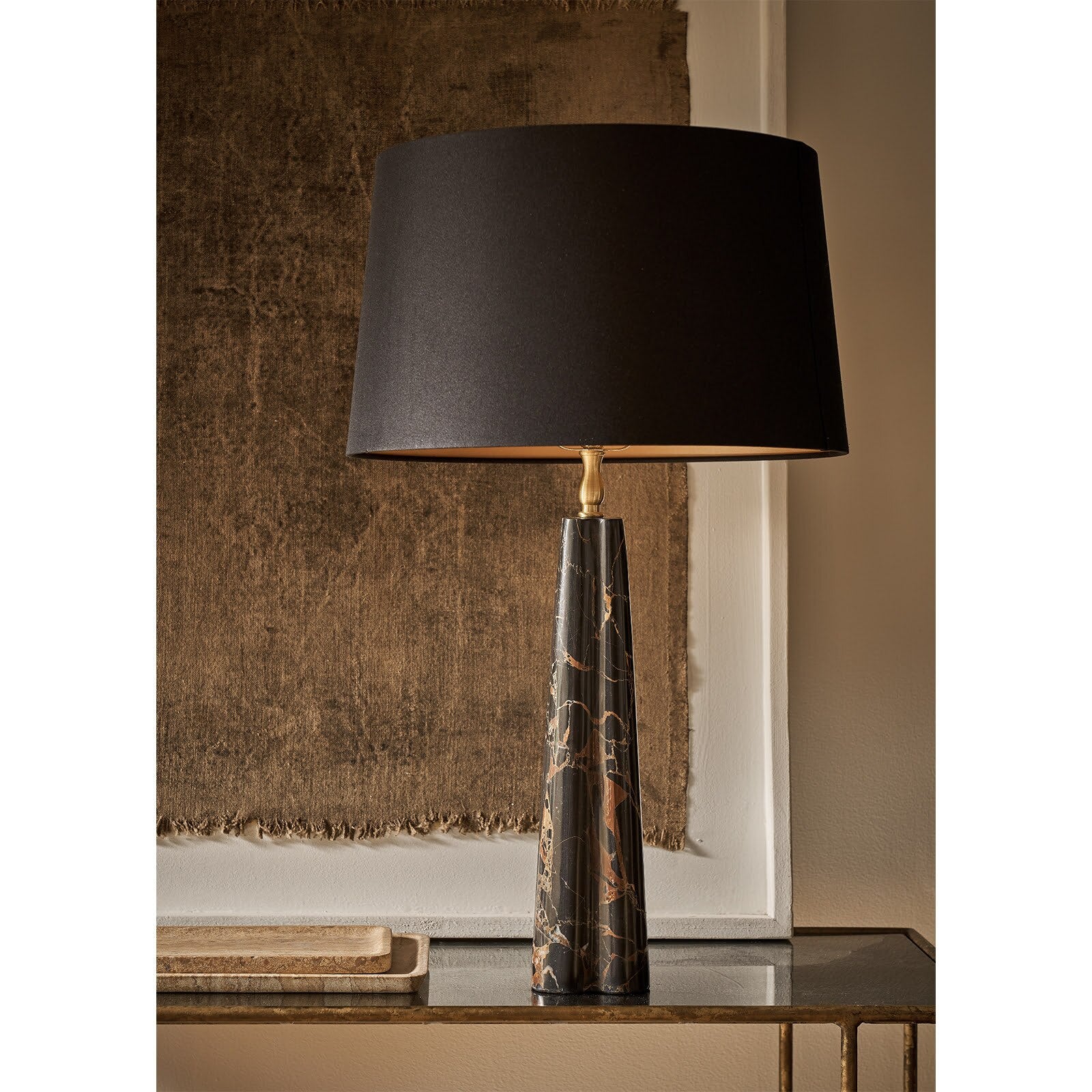 Table lamp with a black shade and marble base on a reflective surface.