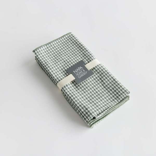 Set of four Viola Dinner Napkins made from soft, verdant green cotton, folded and tied with a grosgrain ribbon.