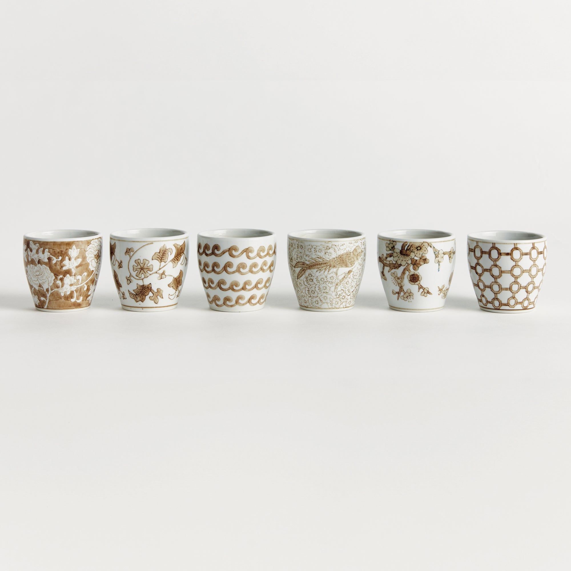 Set of six ceramic cups with decorative patterns on a white background