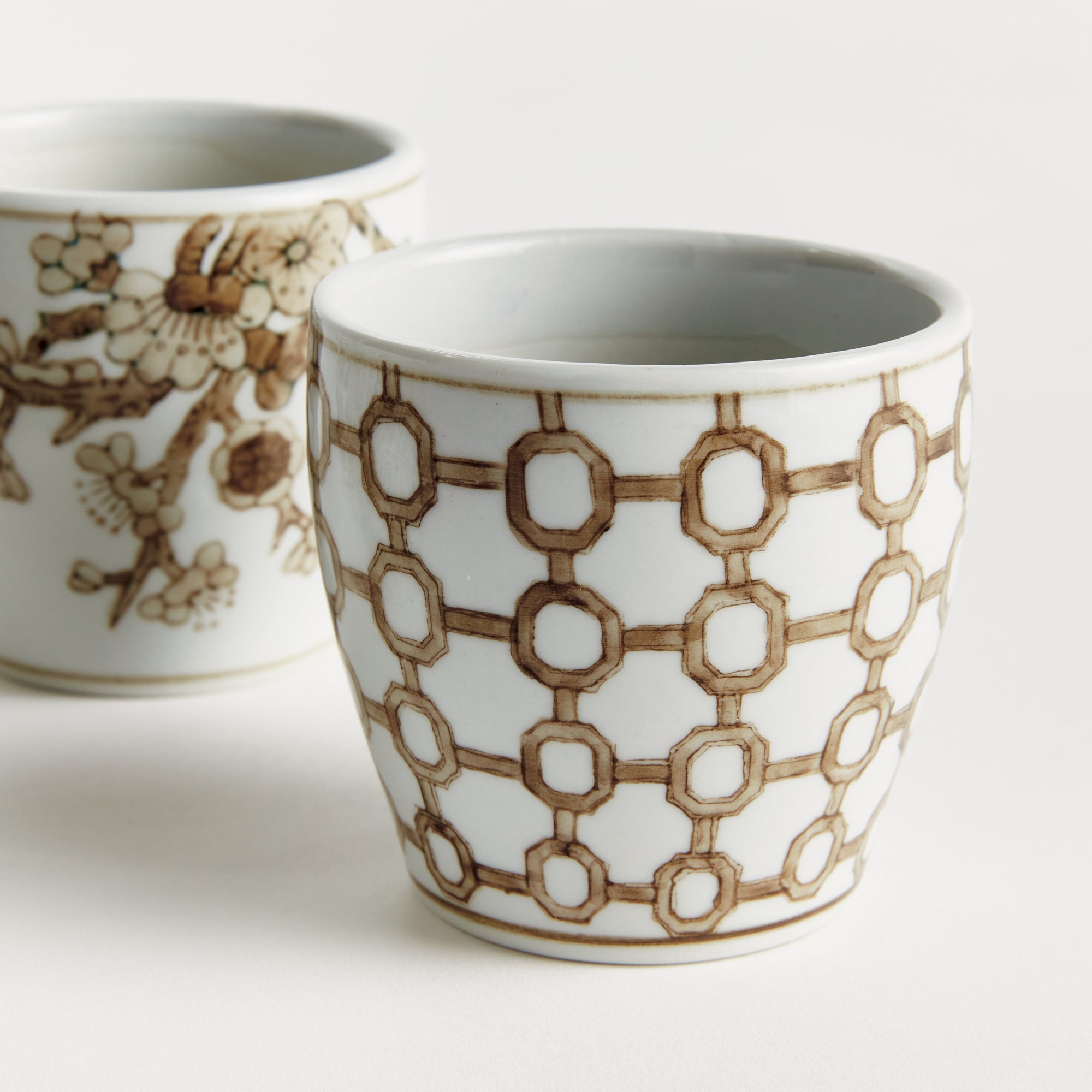 Two ceramic cups with decorative patterns on a white background