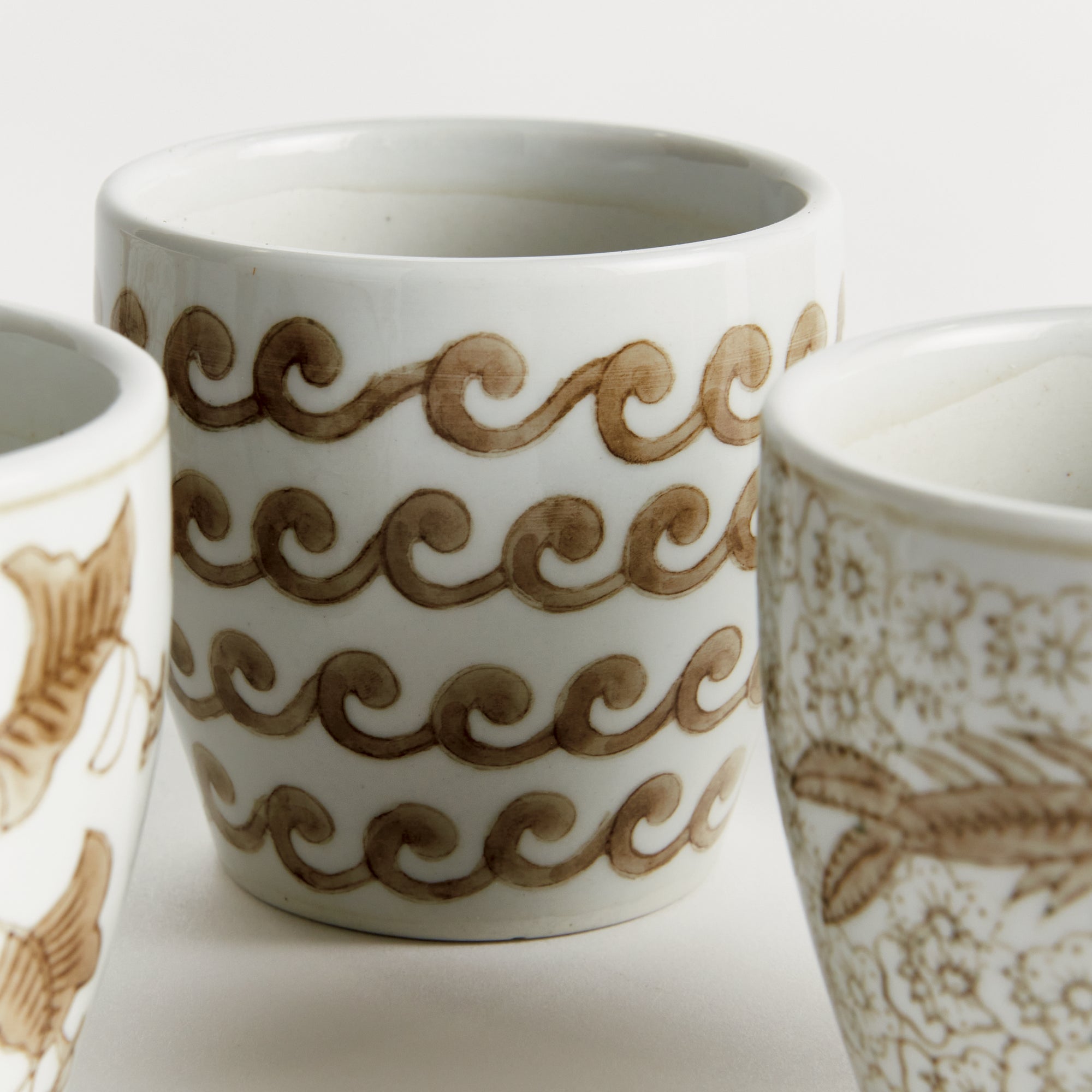 Three ceramic cups with decorative patterns on a white background