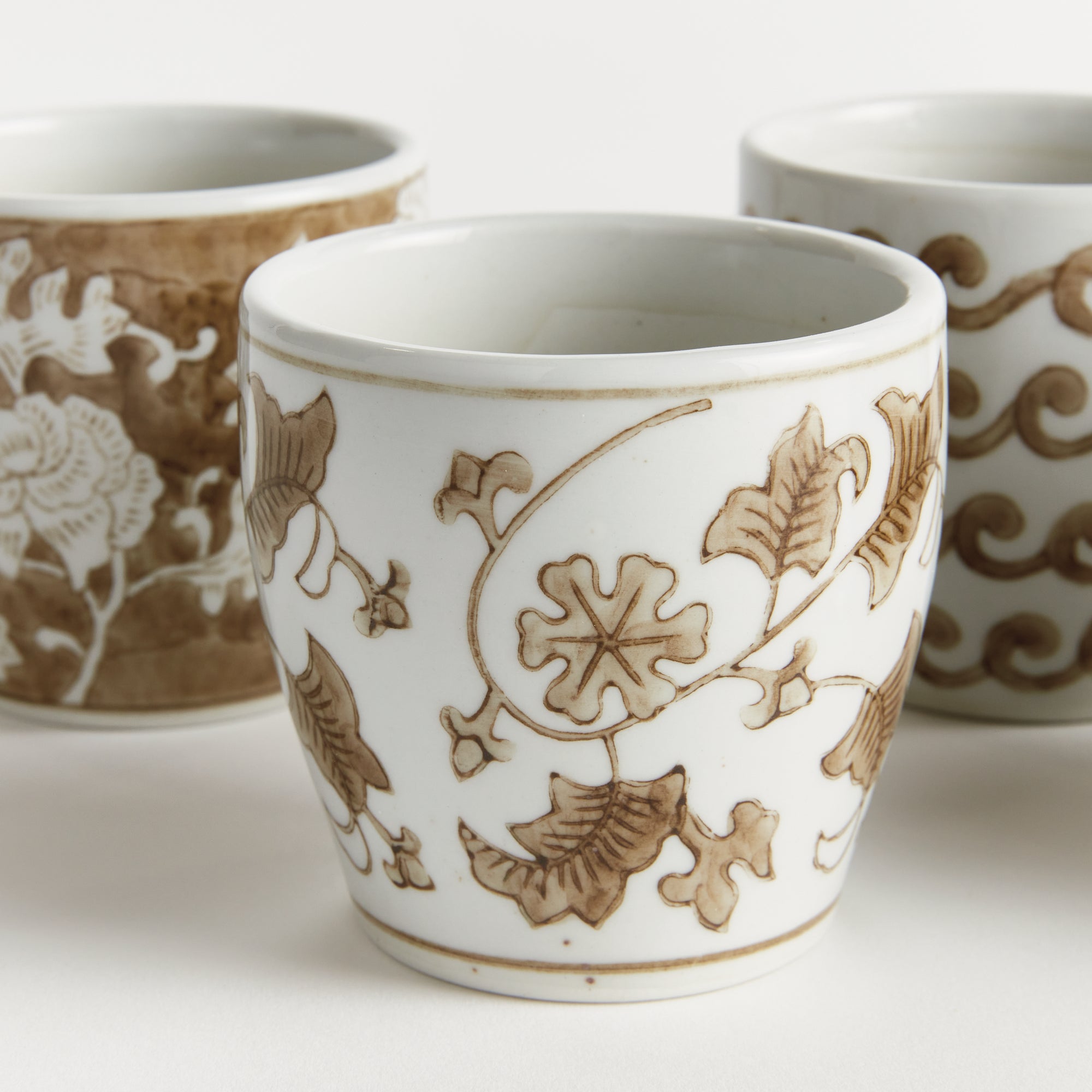 White ceramic cup with brown floral patterns on a white background