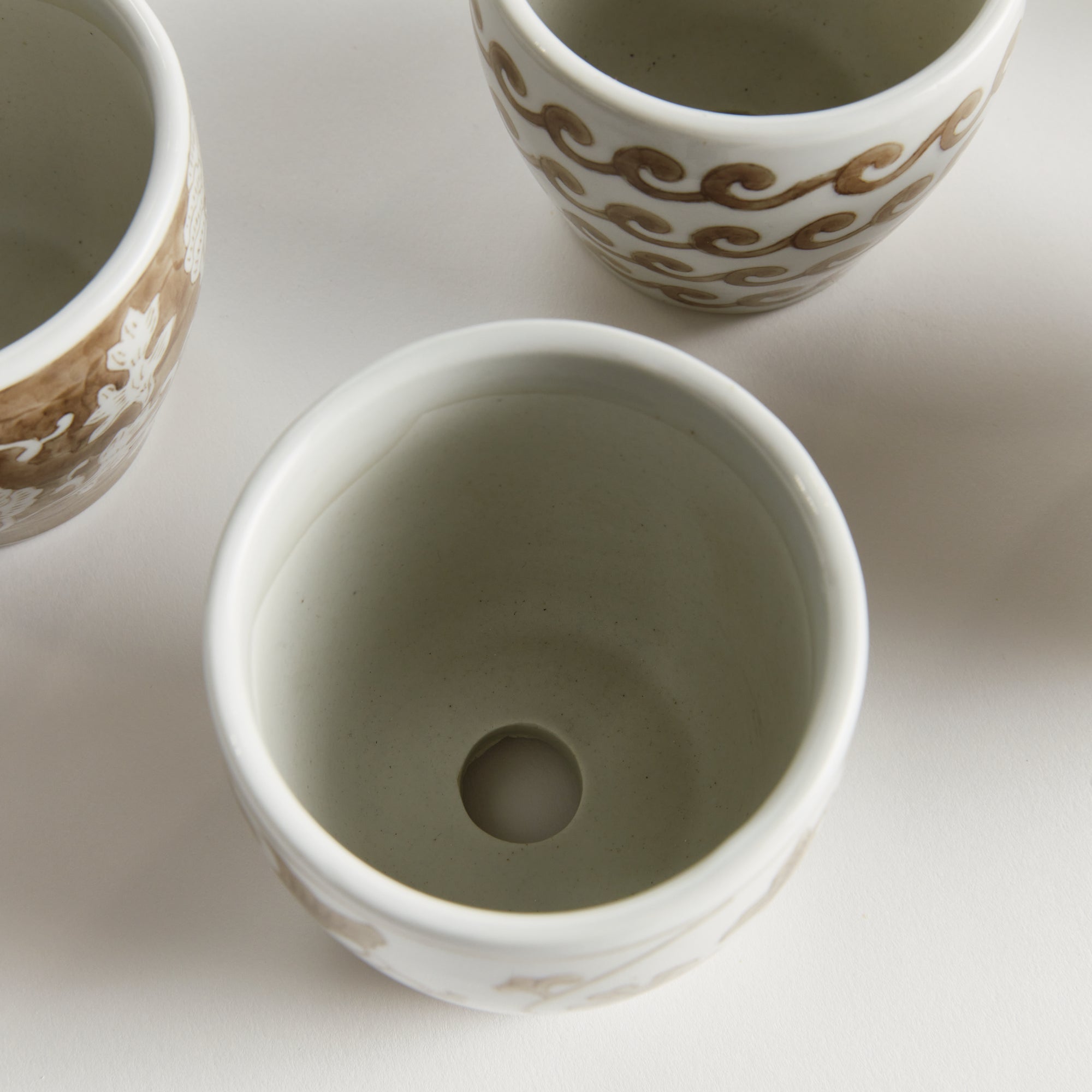 Three ceramic cups with decorative patterns on a light background