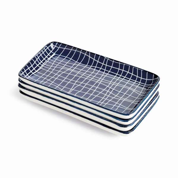 A set of four small, rectangular porcelain serving trays with a modern dark blue and white abstract design, arranged neatly on a table.