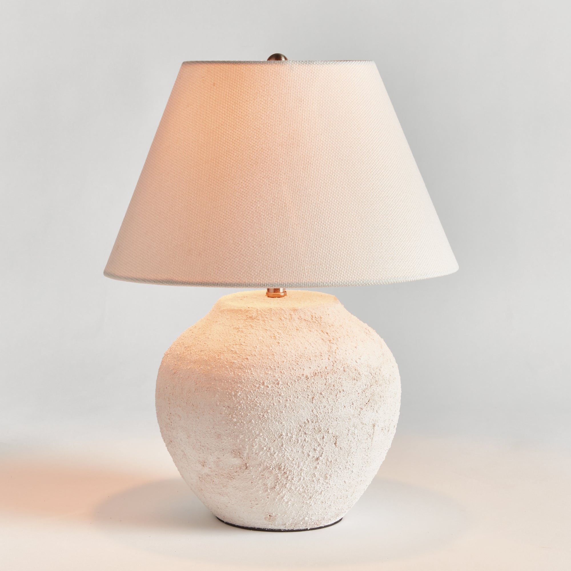 Theo Table lamp with textured white base and beige lampshade on a light gray background