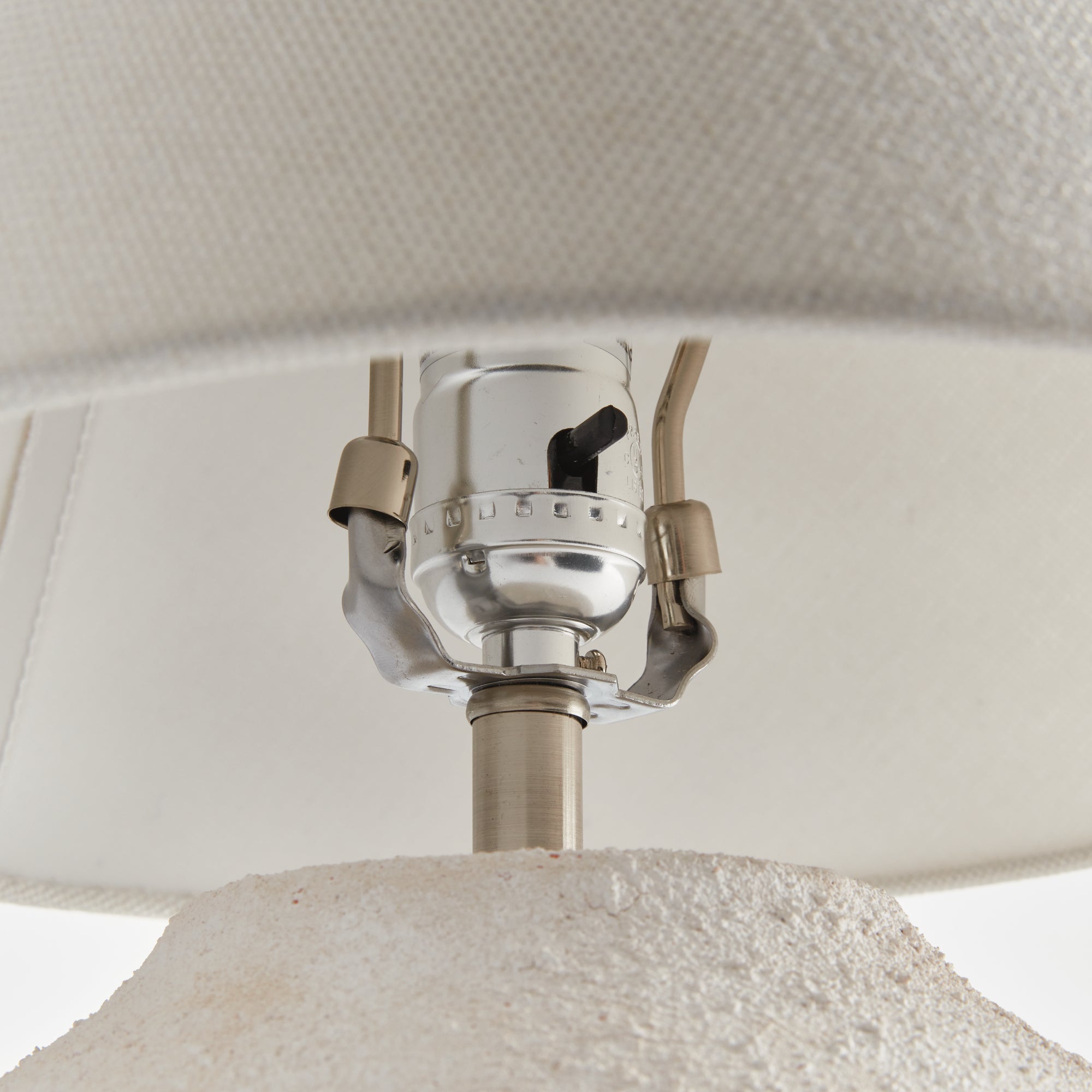 Theo Lamp Close-up of a lampshade with a metallic fitting and white fabric.